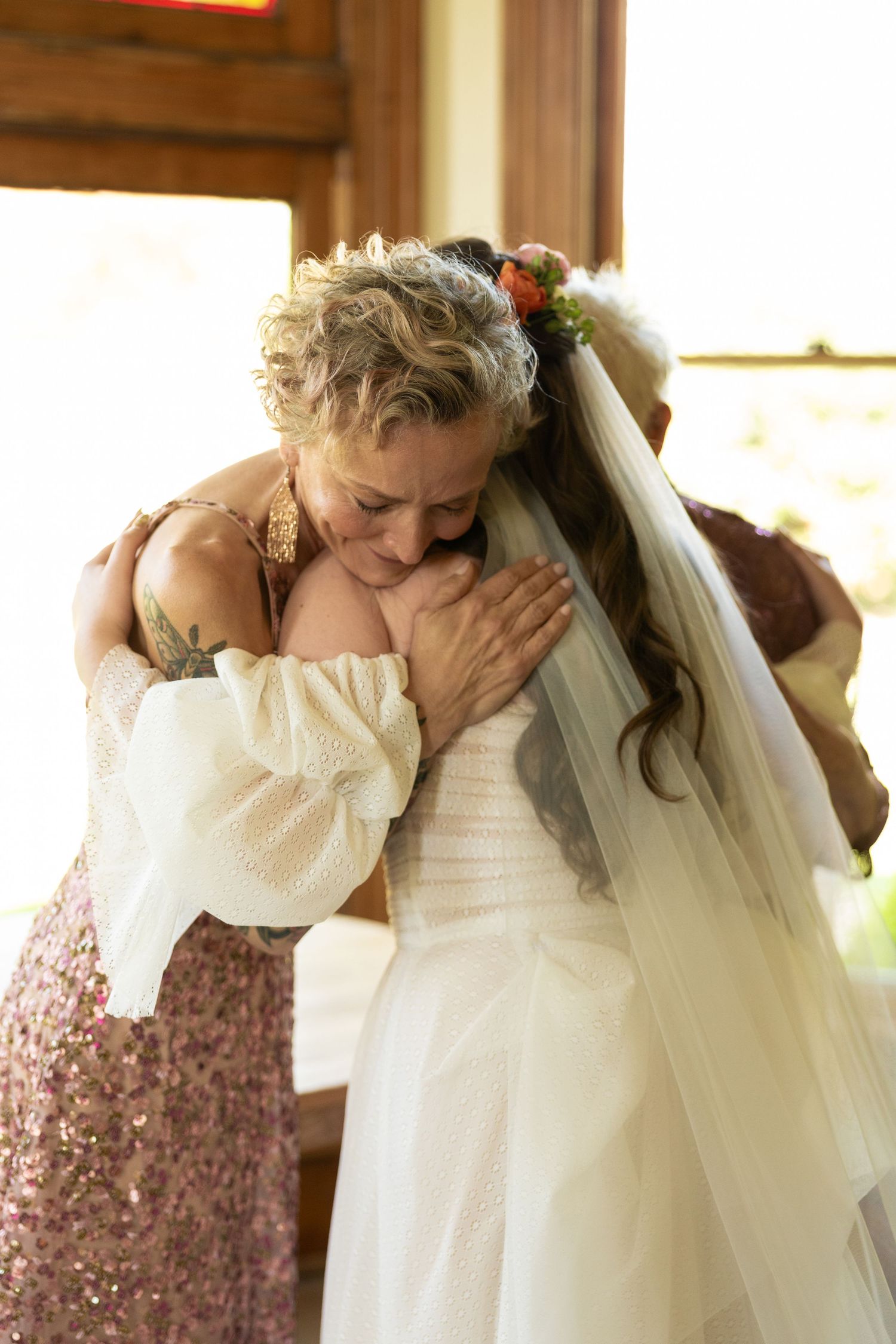 An intimate embrace shared between attendees at a wedding celebration with soft lighting.