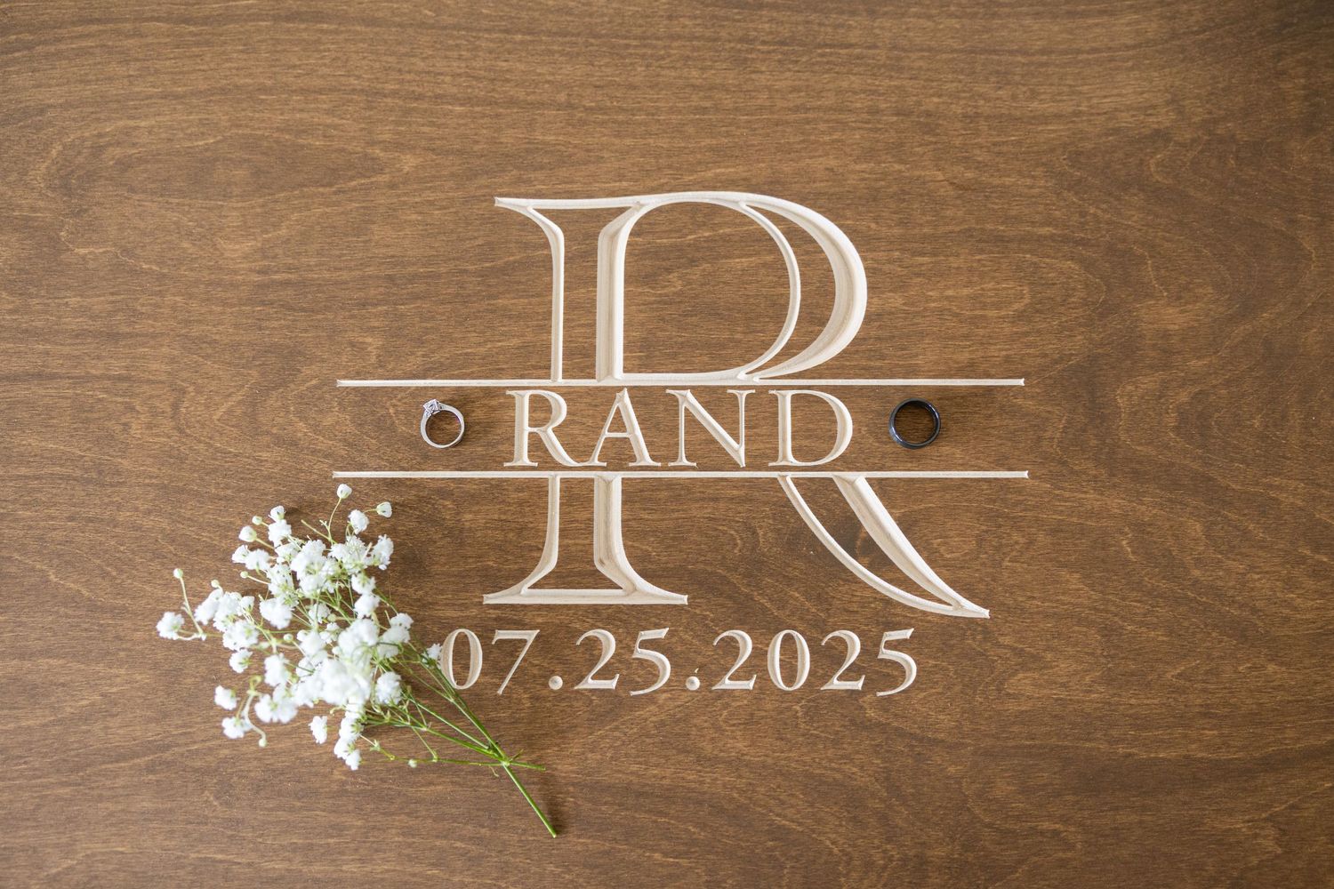 Rustic wooden sign board with elegant white text and floral details displaying wedding date.