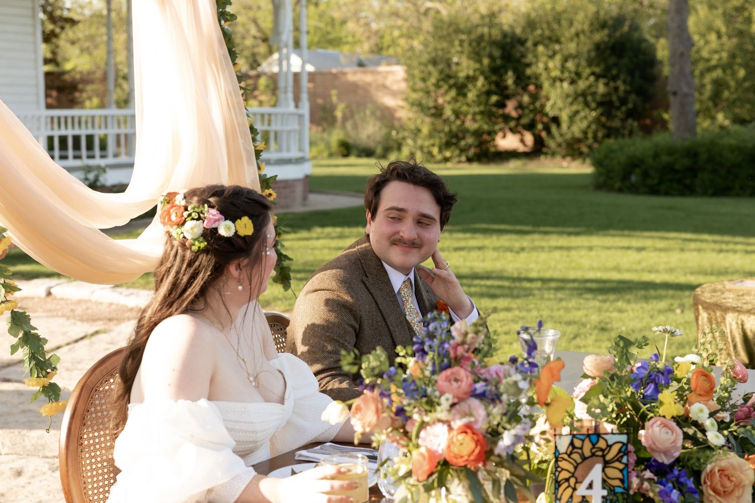 An intimate outdoor wedding reception with colorful floral arrangements on a rustic table.