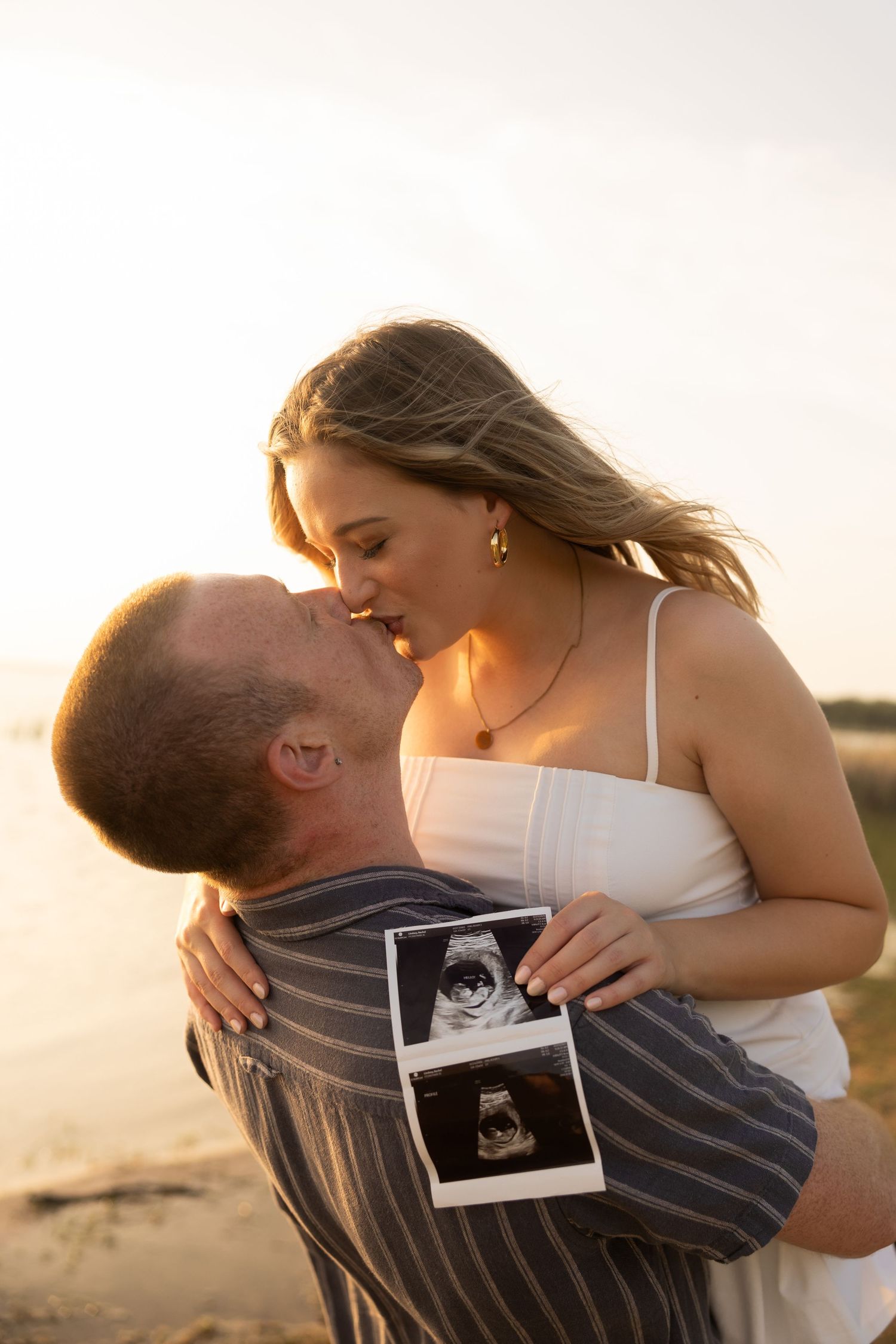 Romantic beach pregnancy announcement photoshoot during golden hour.