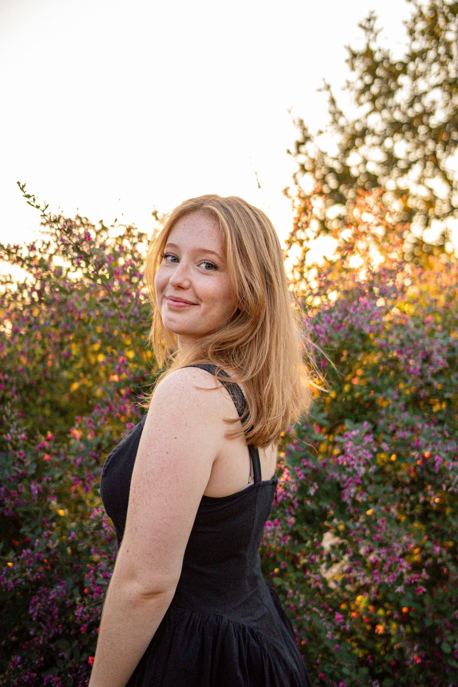 Portrait session in garden with blooming purple flowers during sunset lighting.