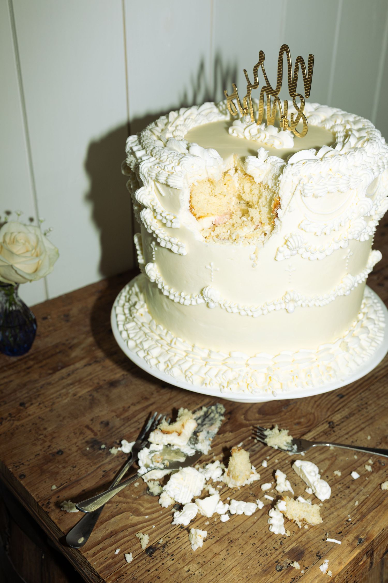 Wedding cake smashed and crumbled on a rustic wooden table during reception festivities.