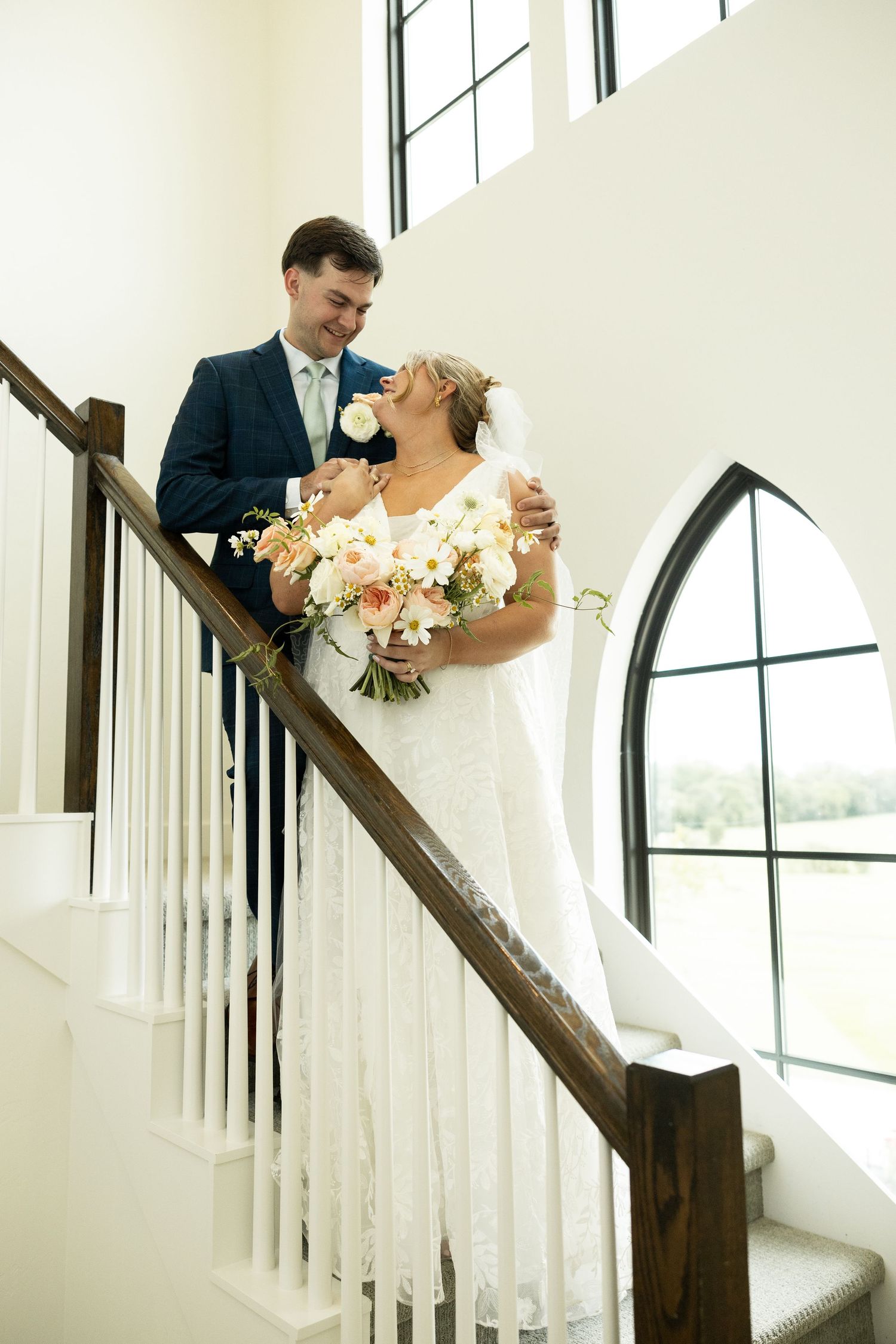 Wedding couple shares an intimate moment on a white staircase.