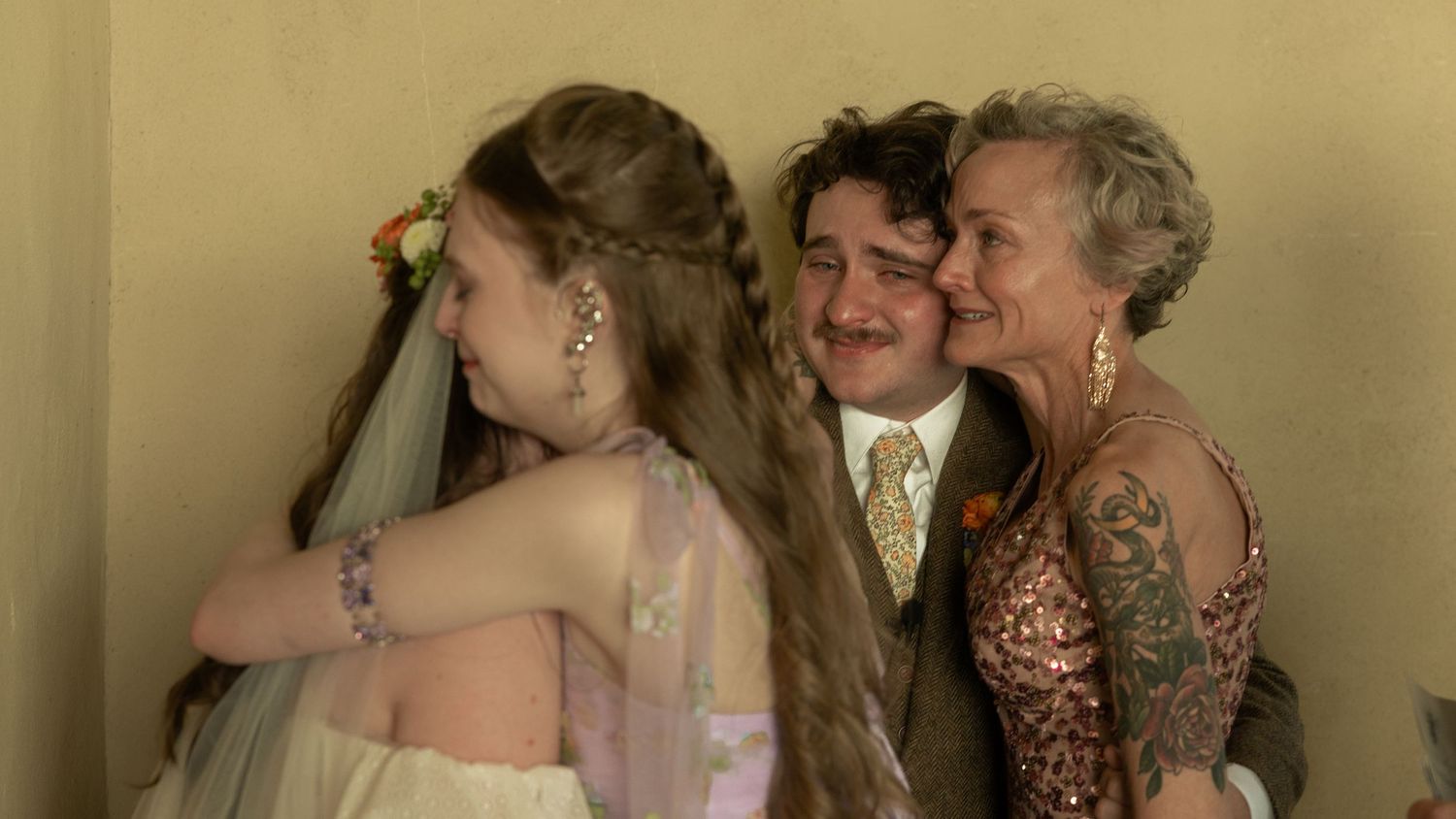 Wedding party members share embraces and reactions during an indoor celebration.