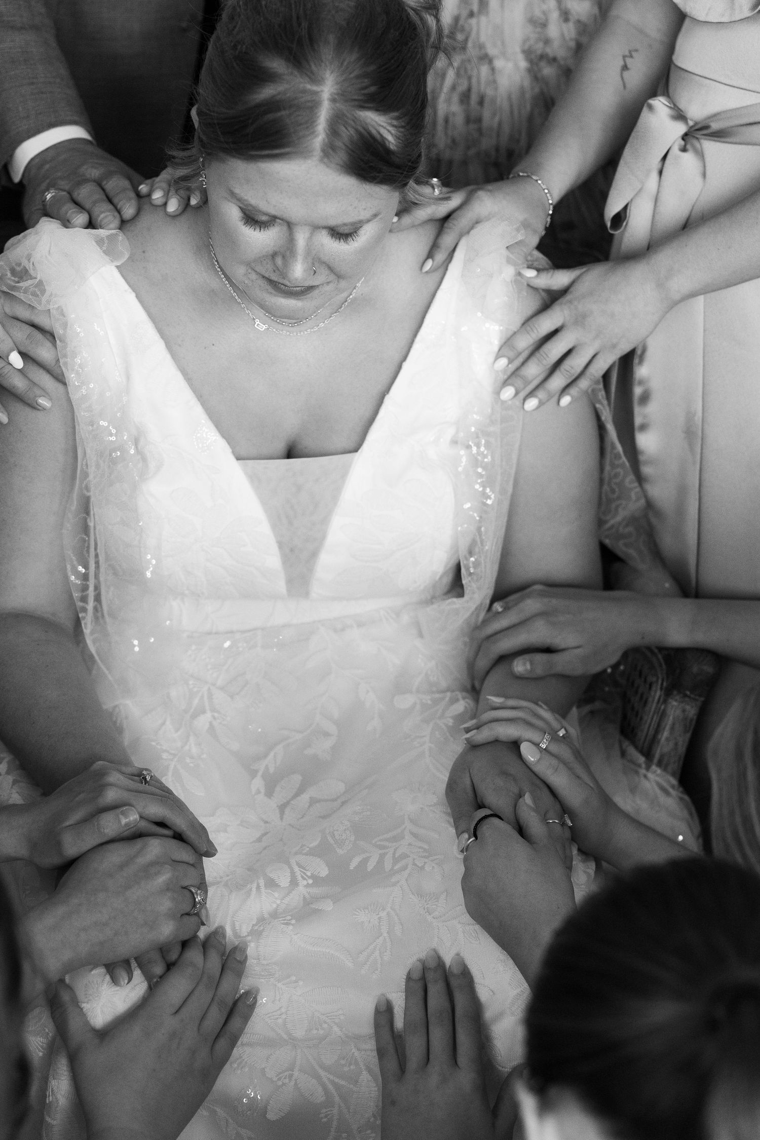 Black and white photo of group surrounding person in white dress.