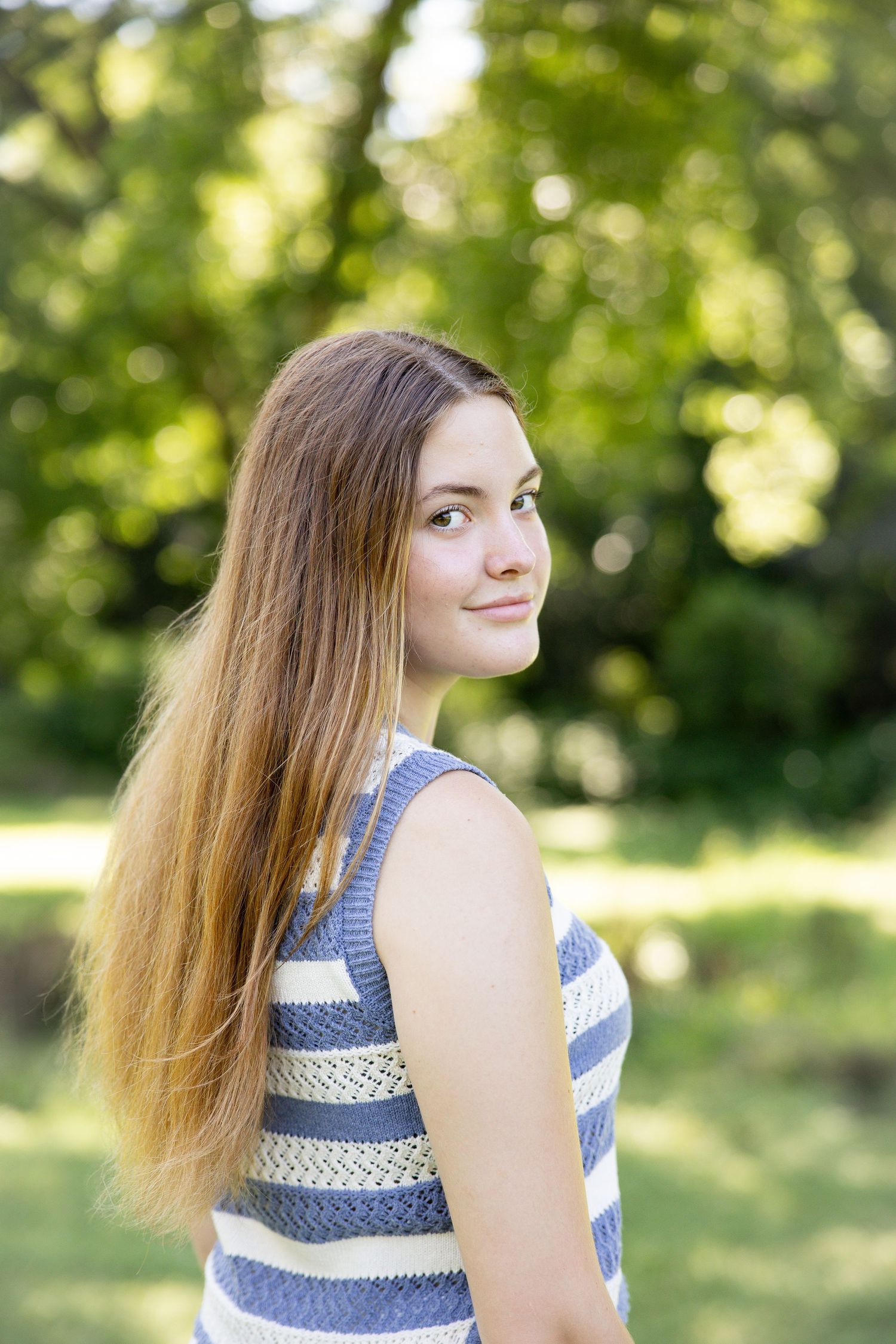 Blue and white striped summer outfit portrait with natural garden backdrop.