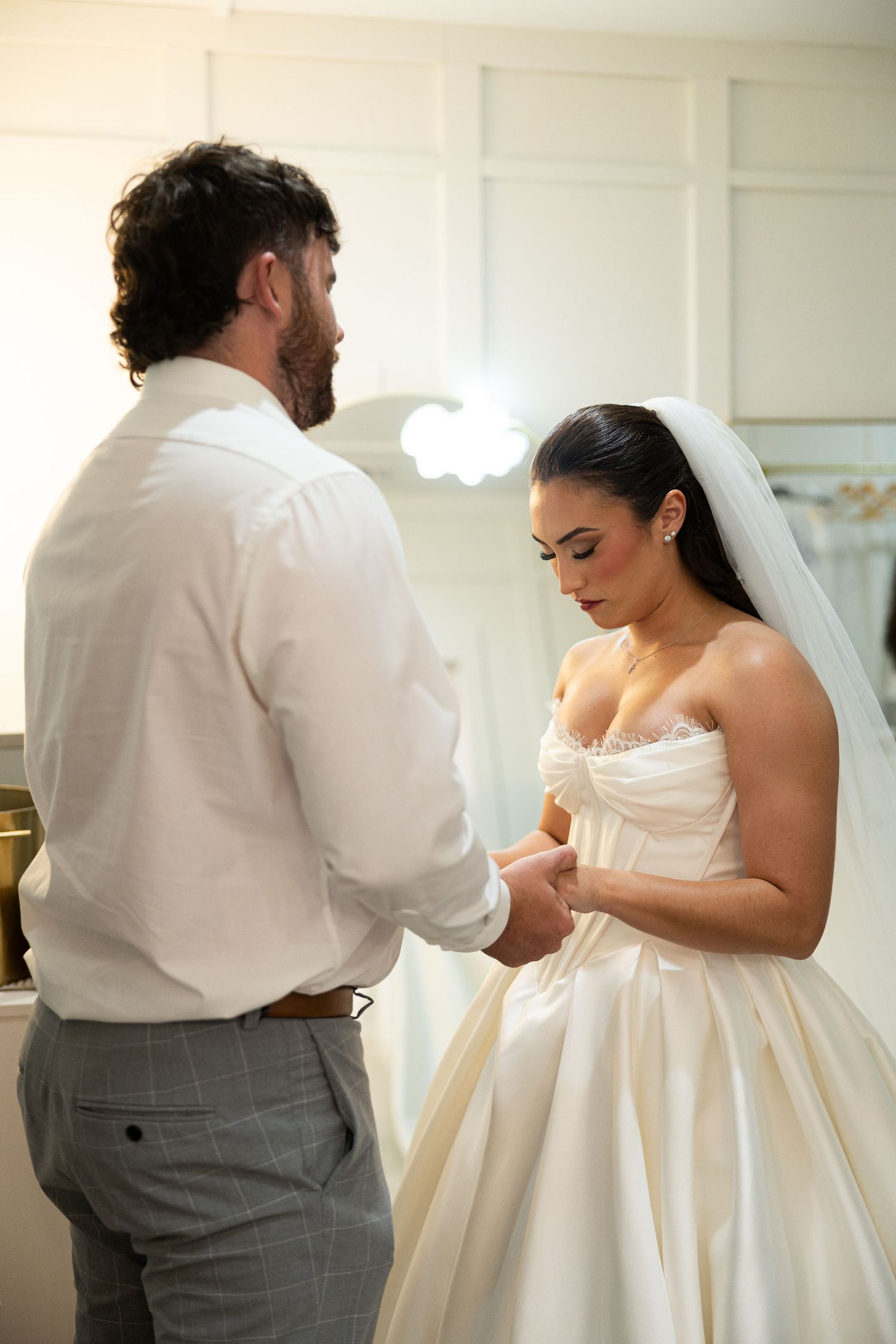Wedding preparation moments showing final dress adjustments in a bright indoor setting.