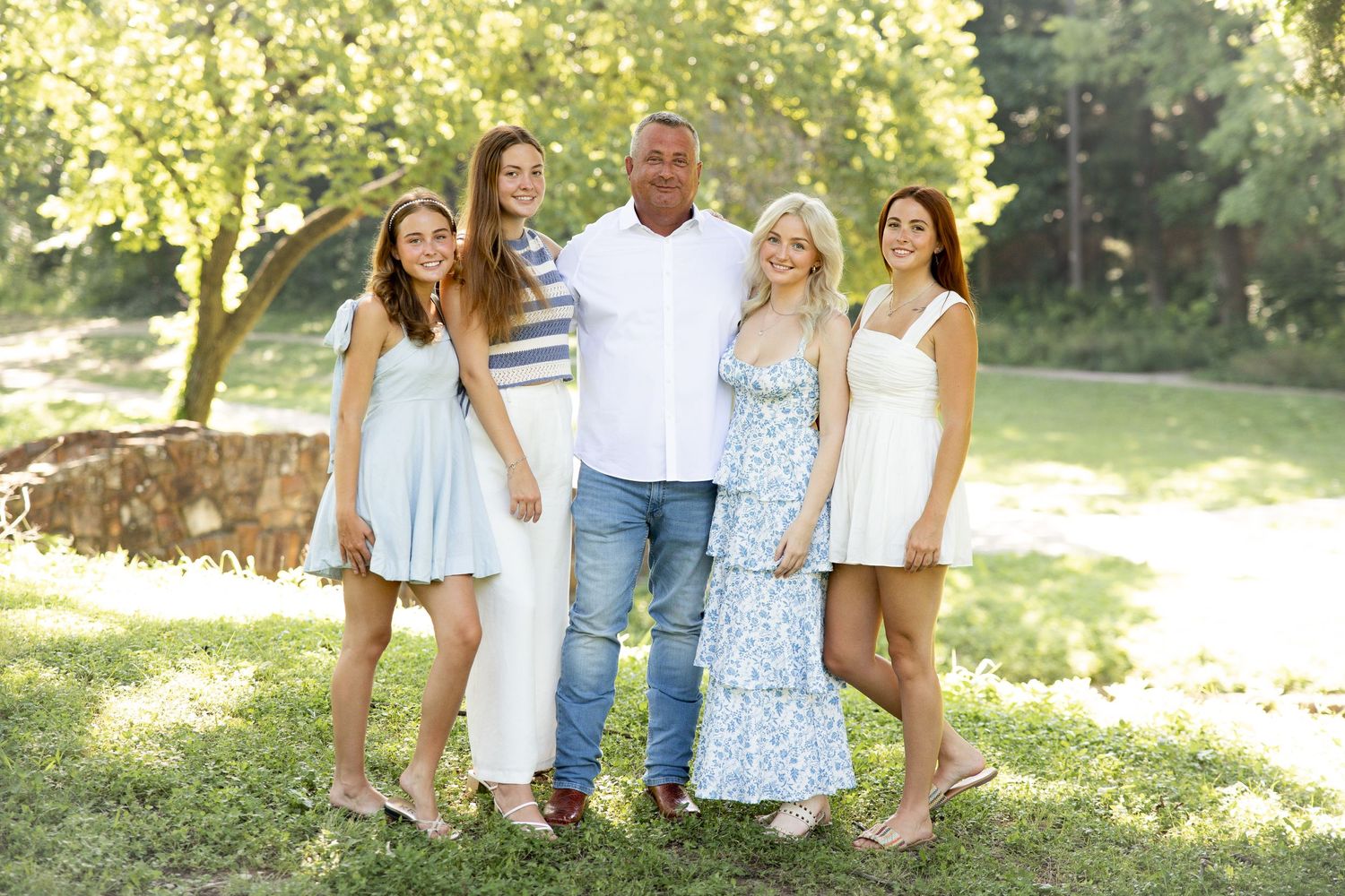 Candid group photo in coordinated white and blue outfits in a sunny garden setting.