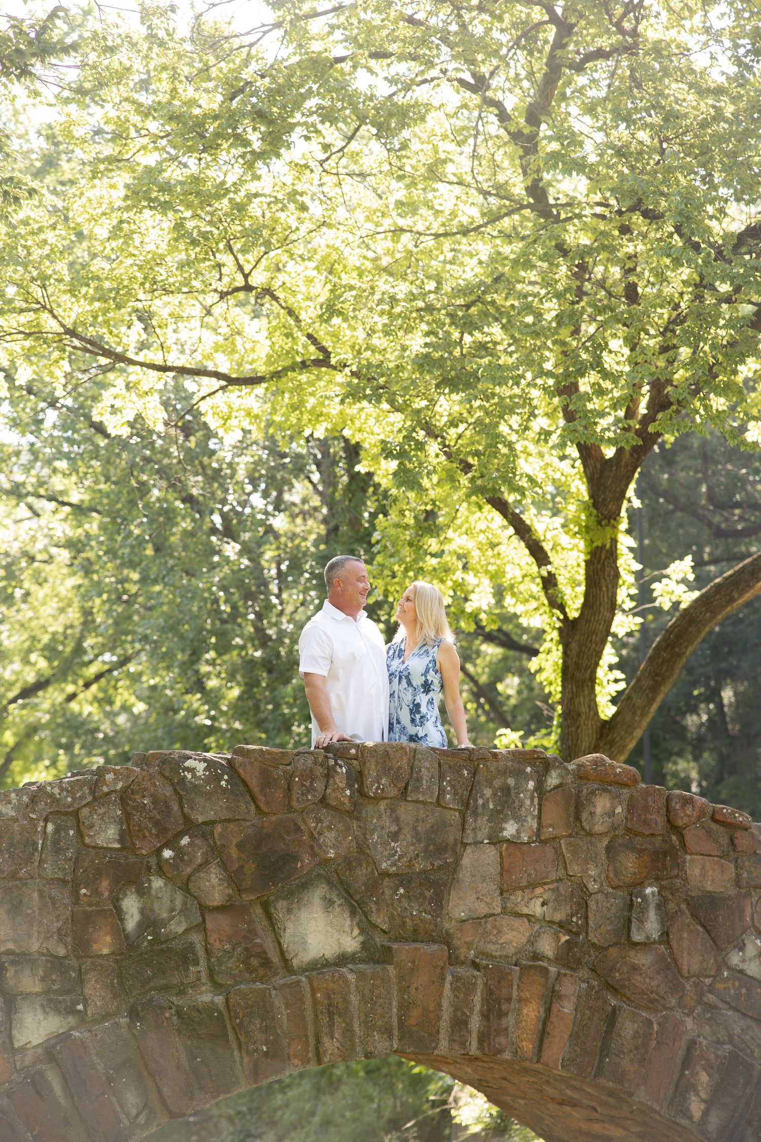 Stone wall portrait session with trees and natural lighting in background.