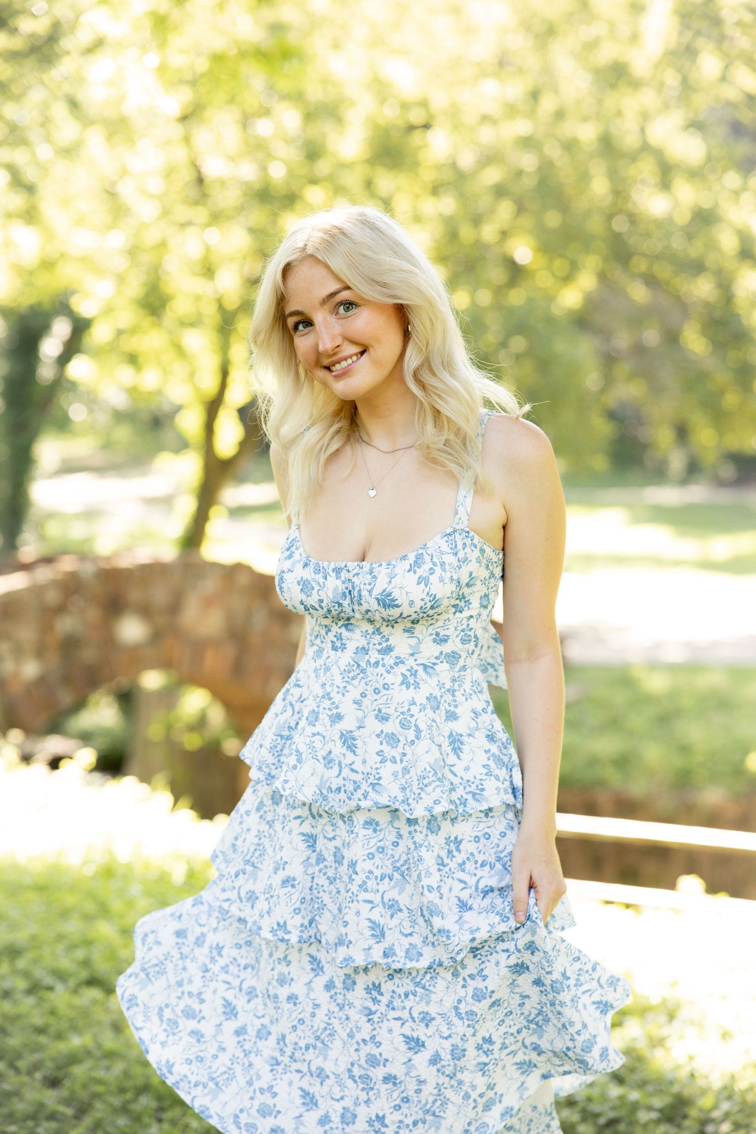 Light blue floral summer dress twirling photo in a sun-dappled garden setting.