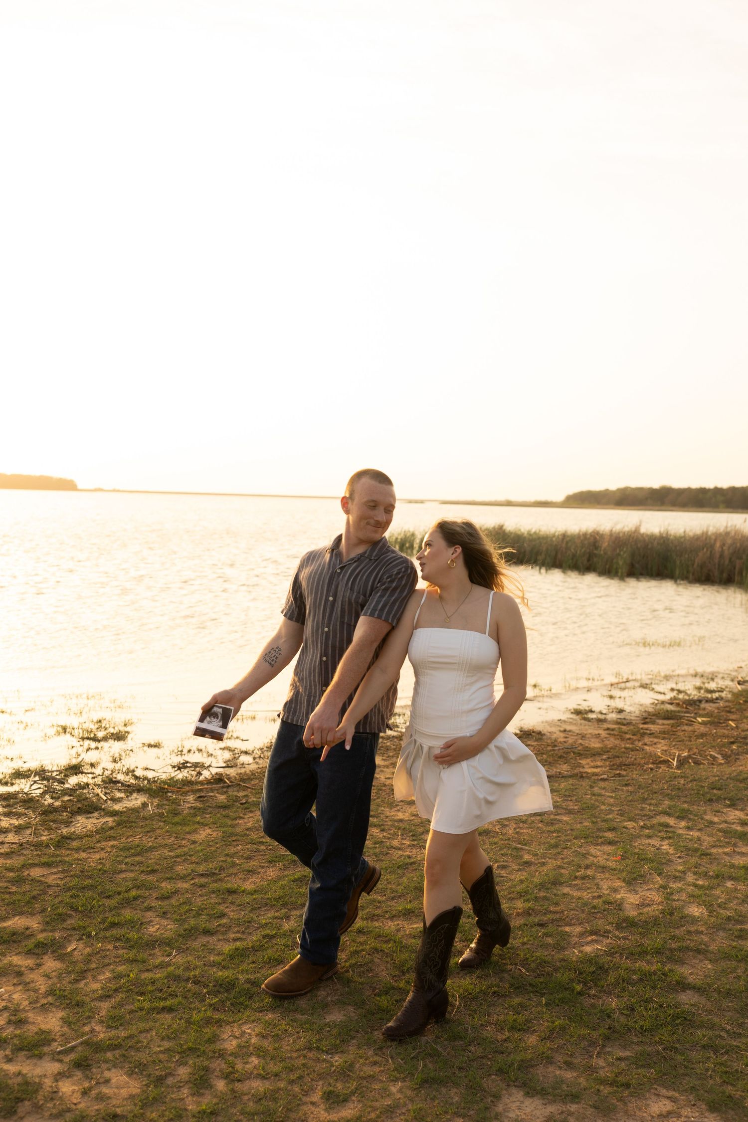 A couple walks together on a beach path during sunset.