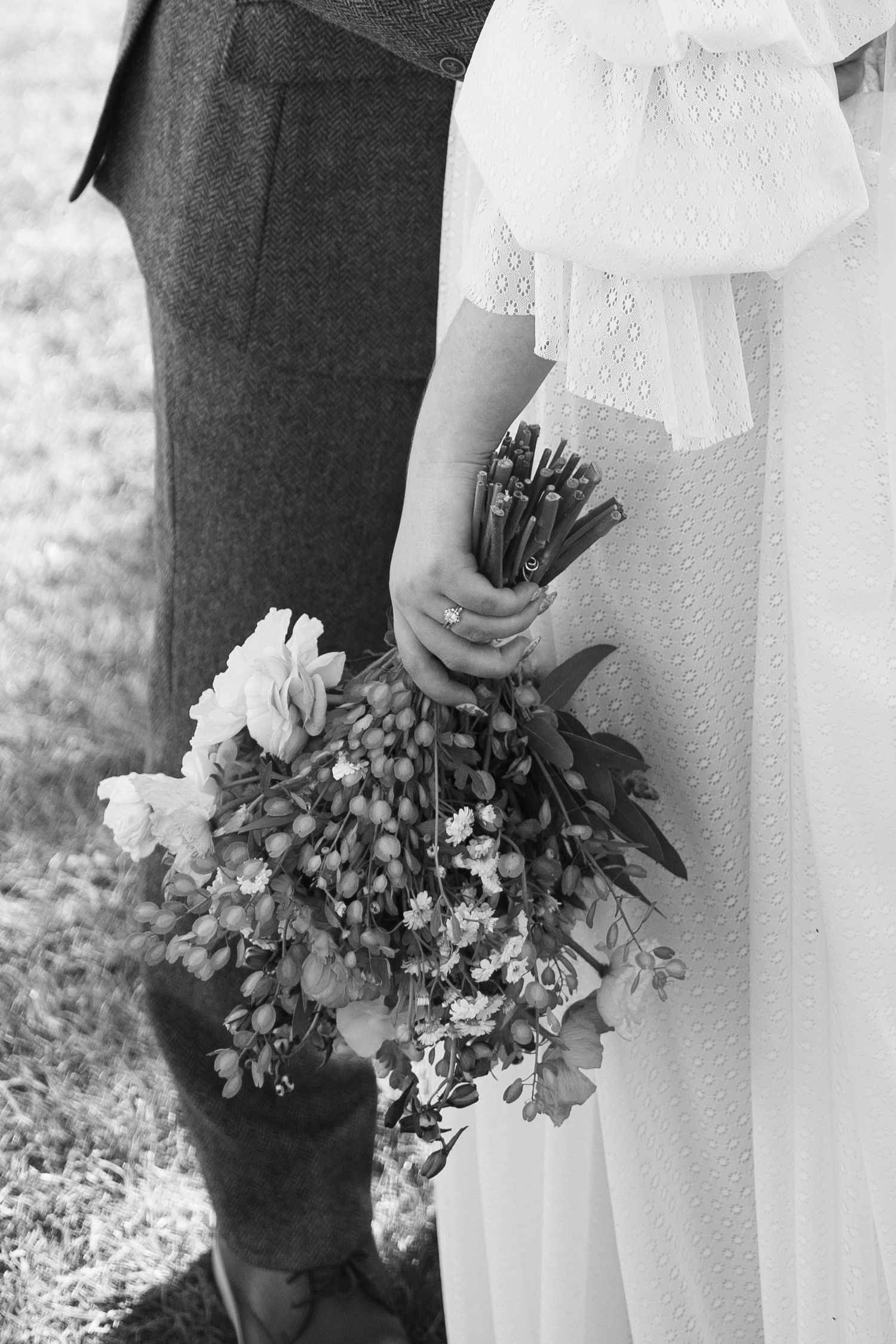 A black and white close-up of a wedding bouquet with delicate flowers and greenery.