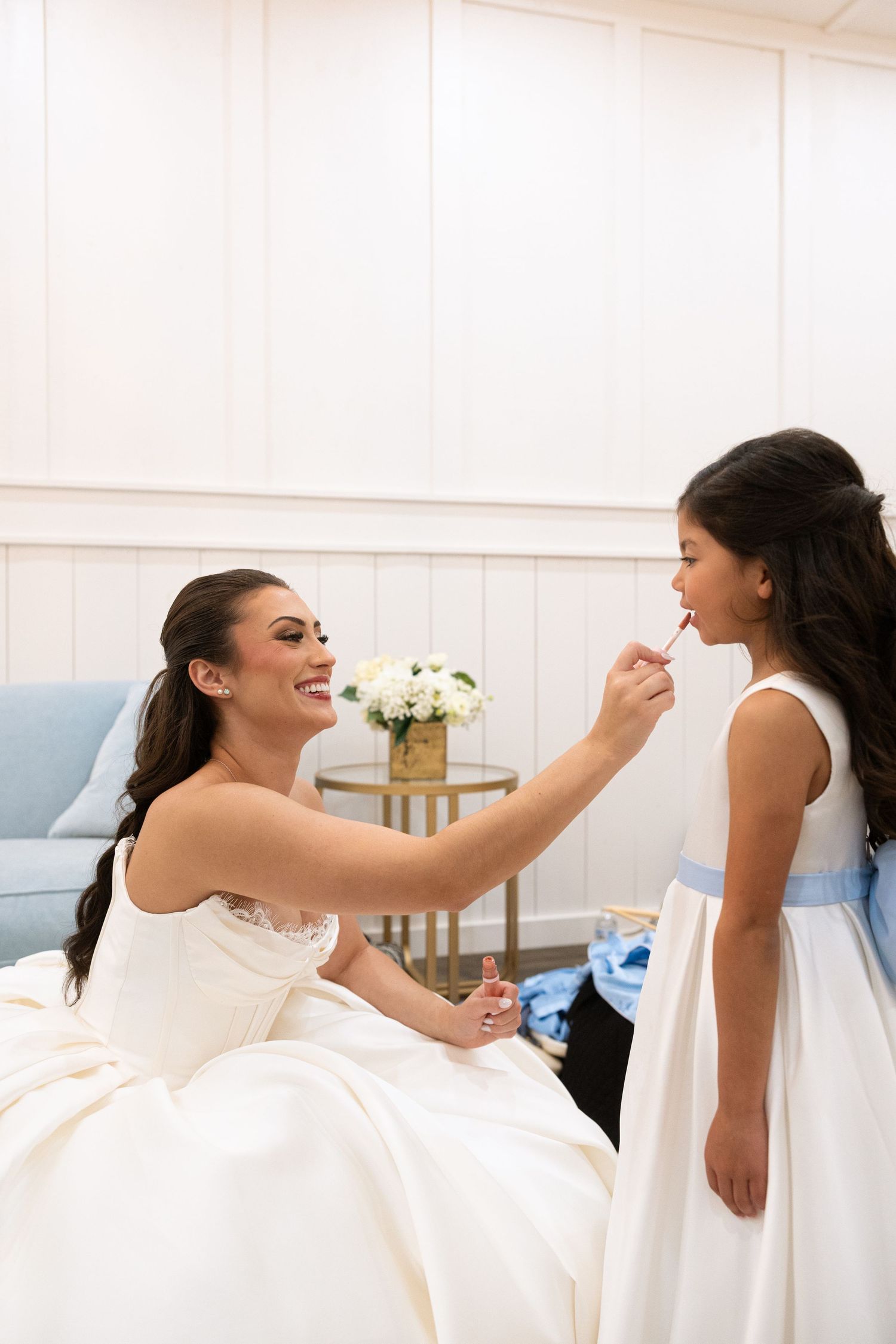 Wedding party members in white dresses share playful moments while getting ready.
