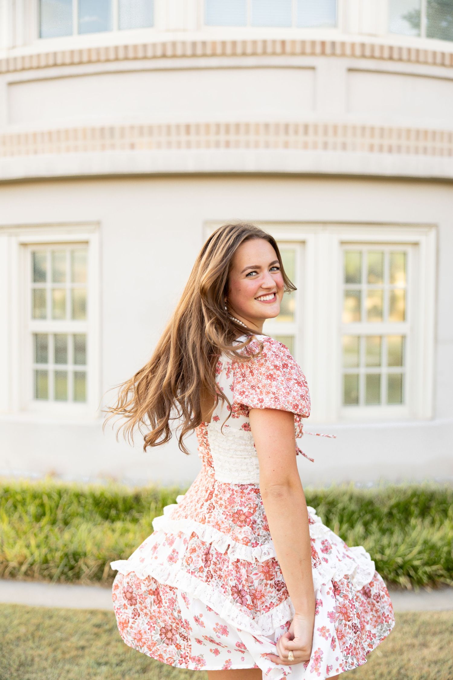 A floral dress twirls against white architectural backdrop during golden hour photography.