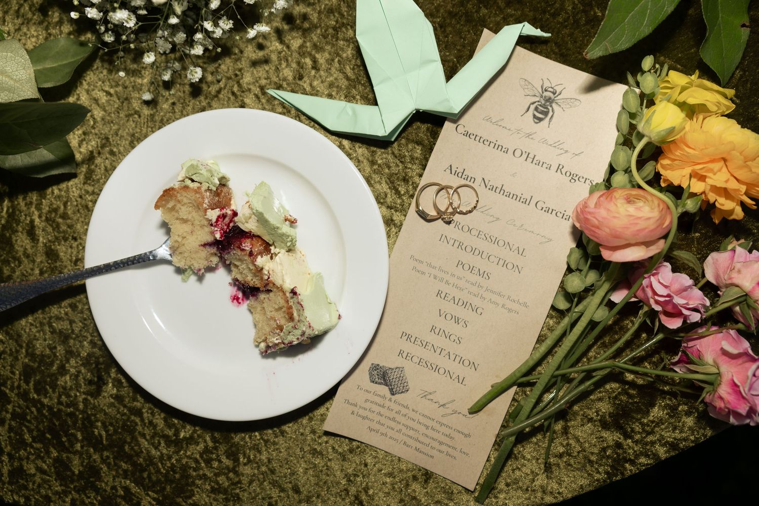 Wedding details with pink flowers and white plates on a textured surface.