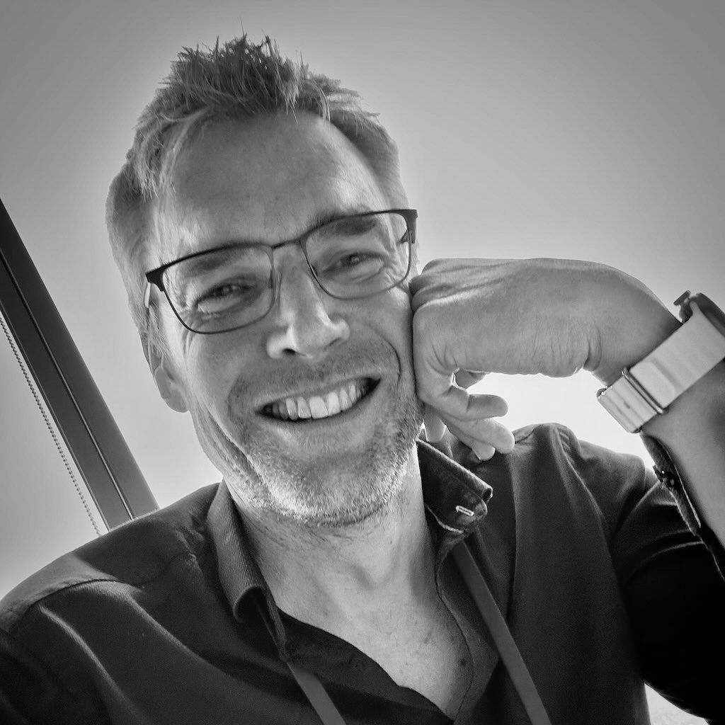 Black and white portraits showing person with glasses smiling in vehicle.
