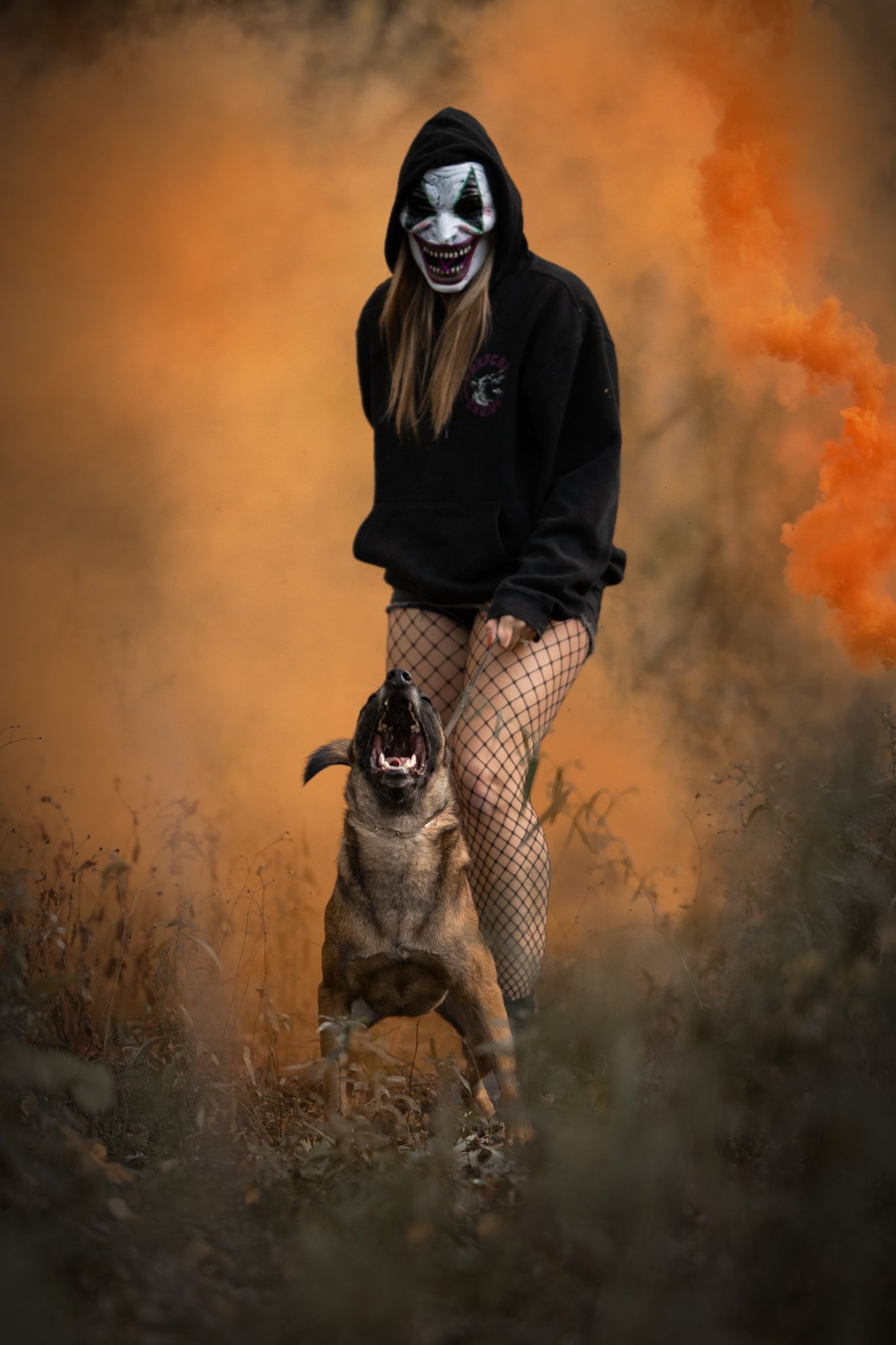 A dark and moody photo series of someone in fishnet stockings and dark clothing crouching in a foggy orange atmosphere.