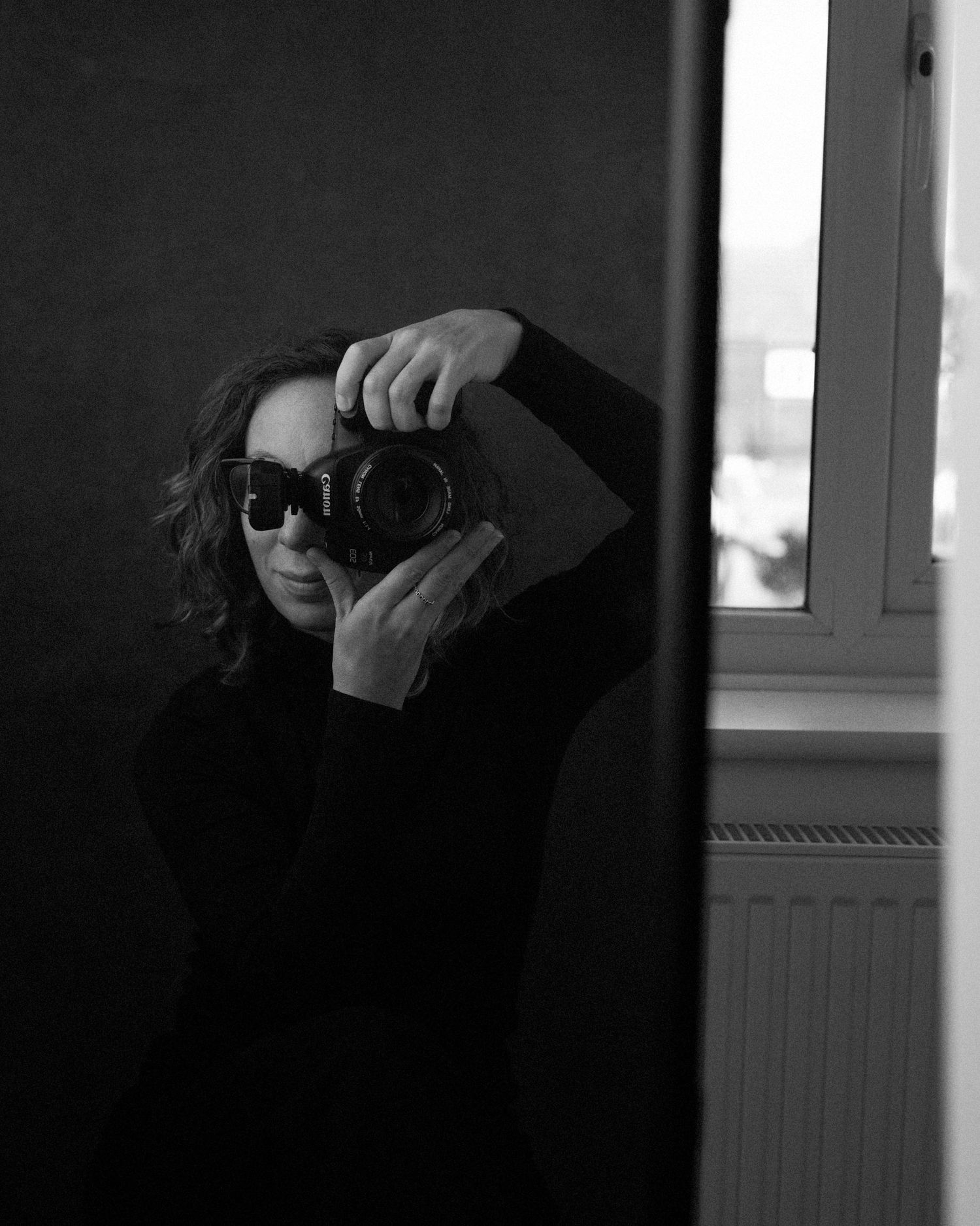 Silhouetted photographer taking pictures in dark room with dramatic lighting.