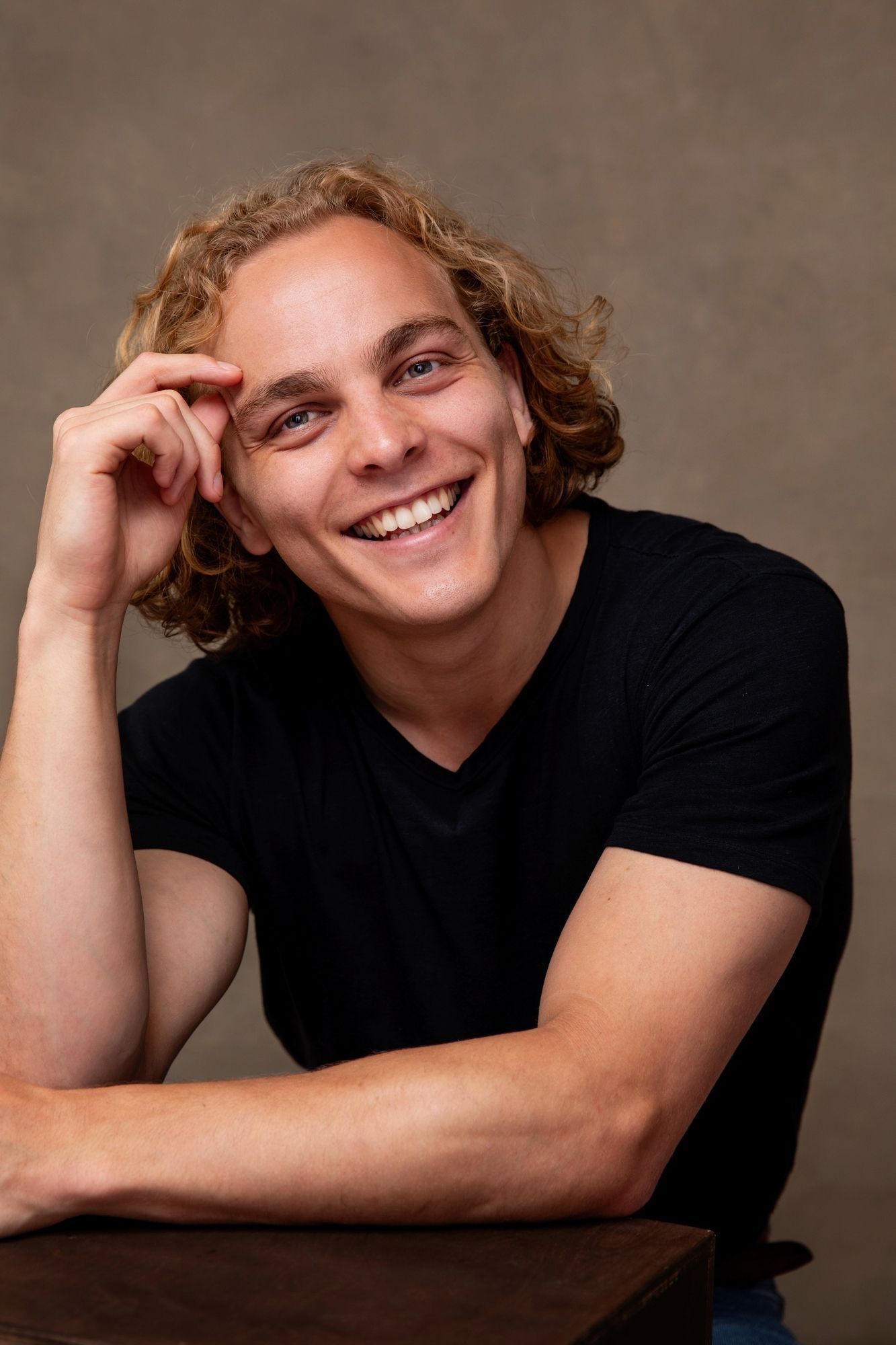 Expressive portrait in black attire against a studio backdrop.