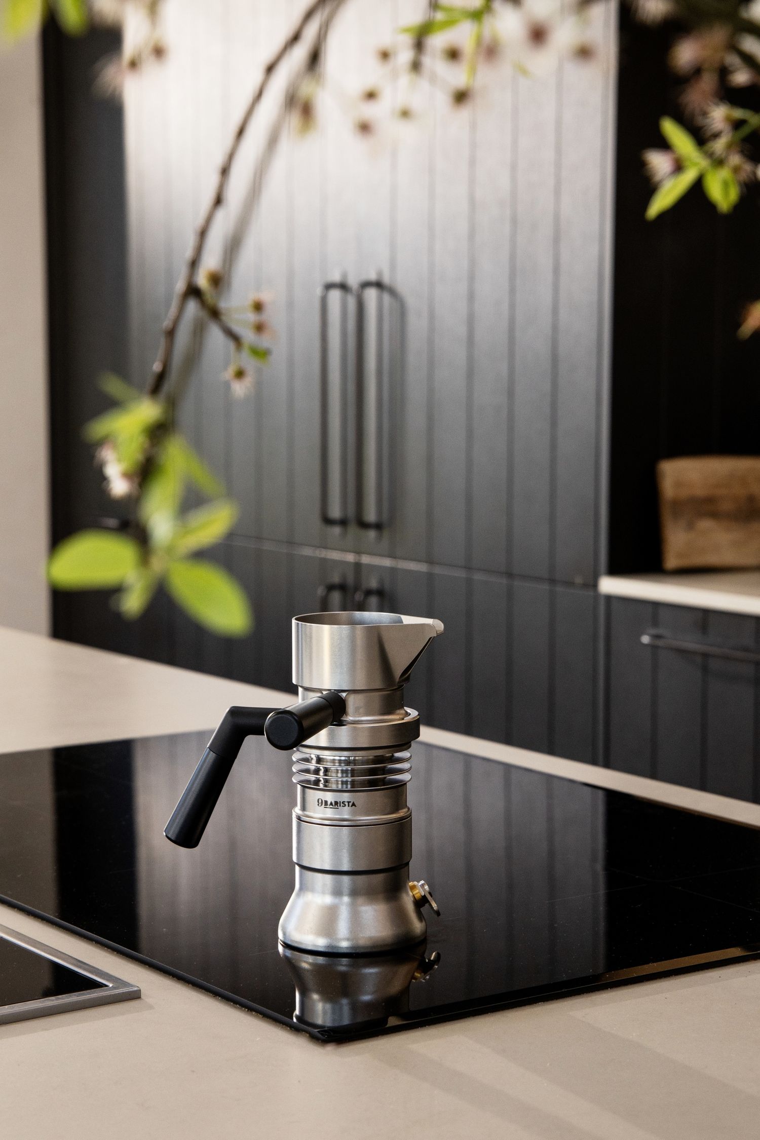 Modern kitchen design featuring sleek black cabinets and stainless steel coffee maker on a black countertop.