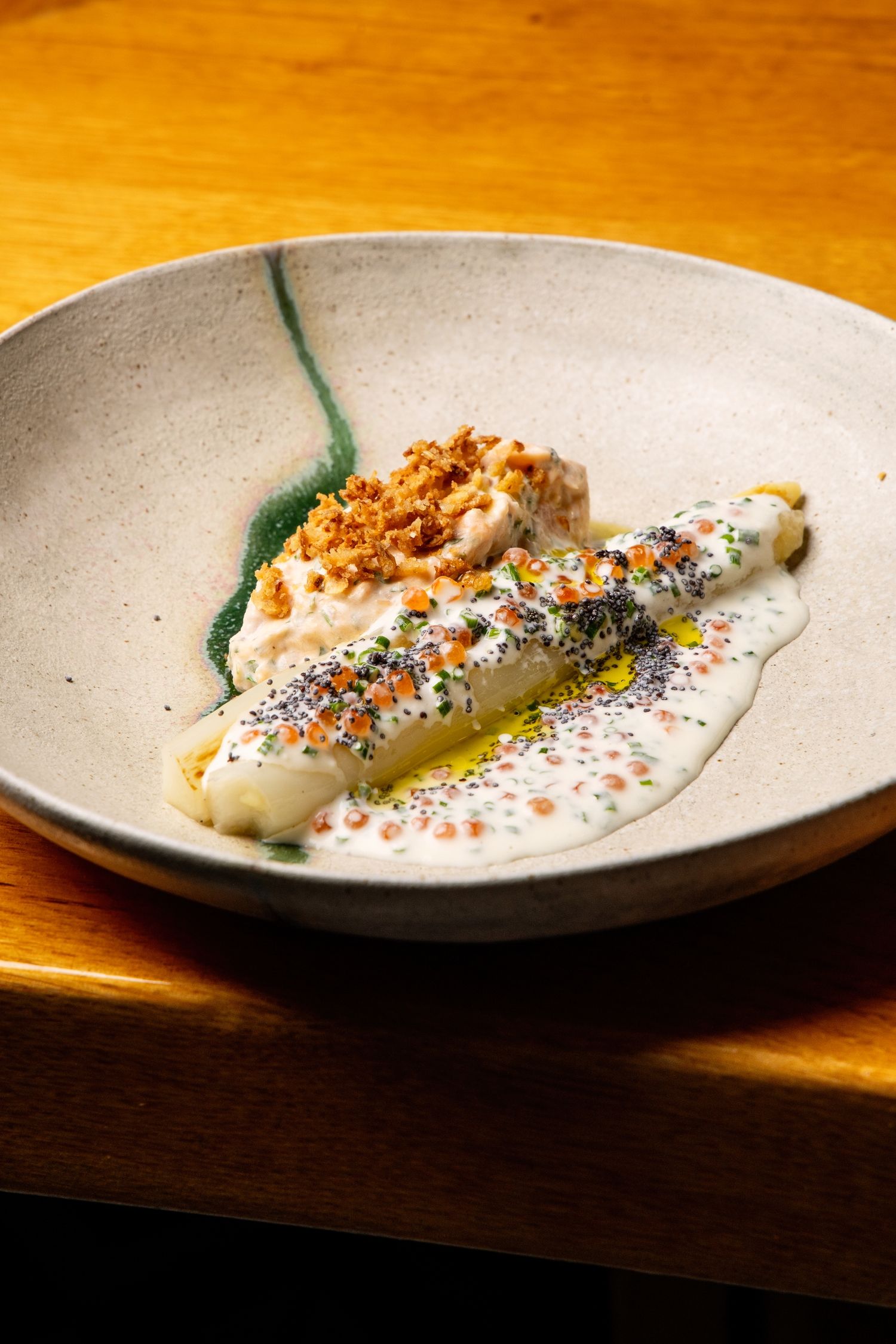 A plated fish dish with colorful spices and herbs served on a rustic wooden surface in dramatic lighting.
