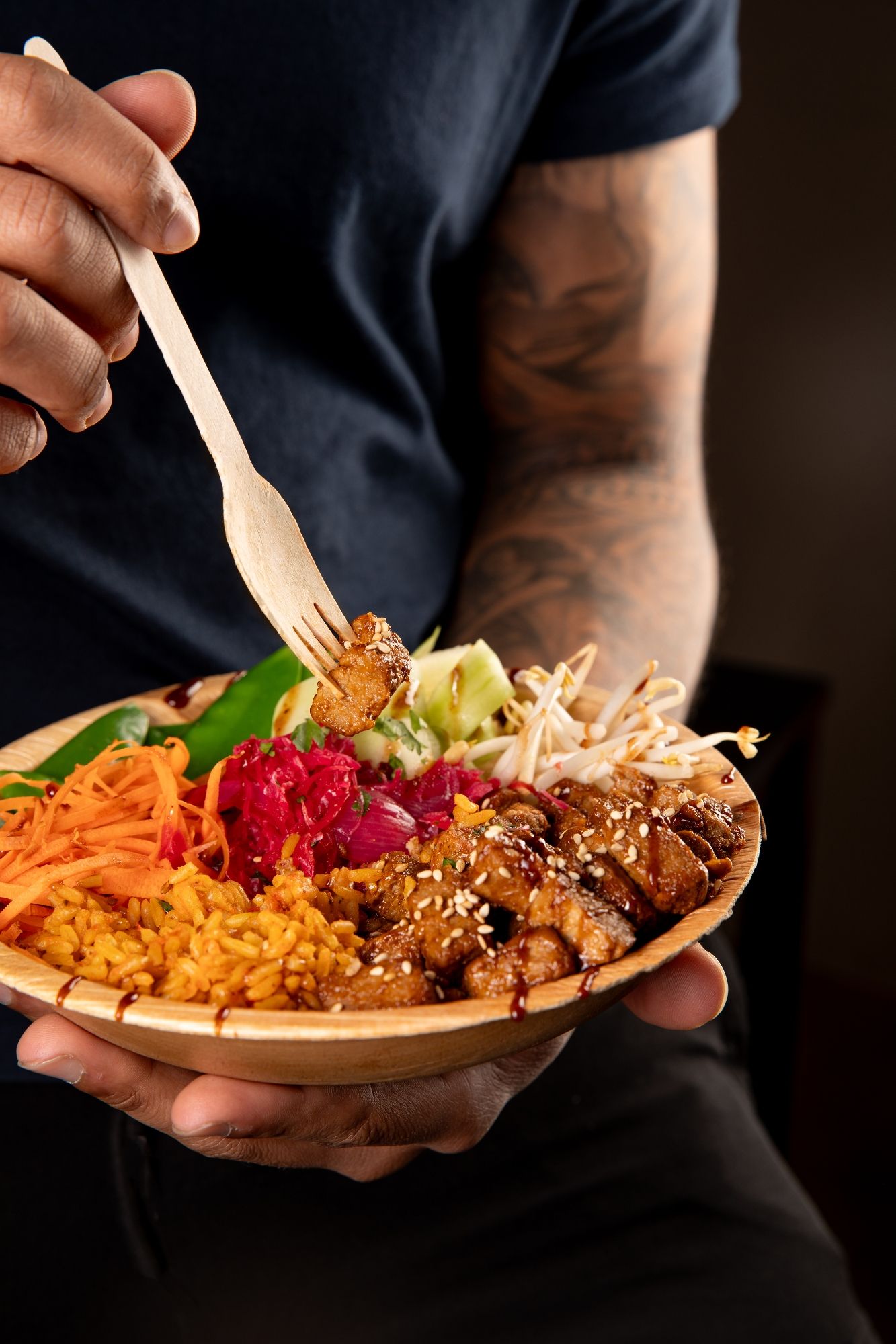 Colorful plant-based food platter being served in a wooden bowl.
