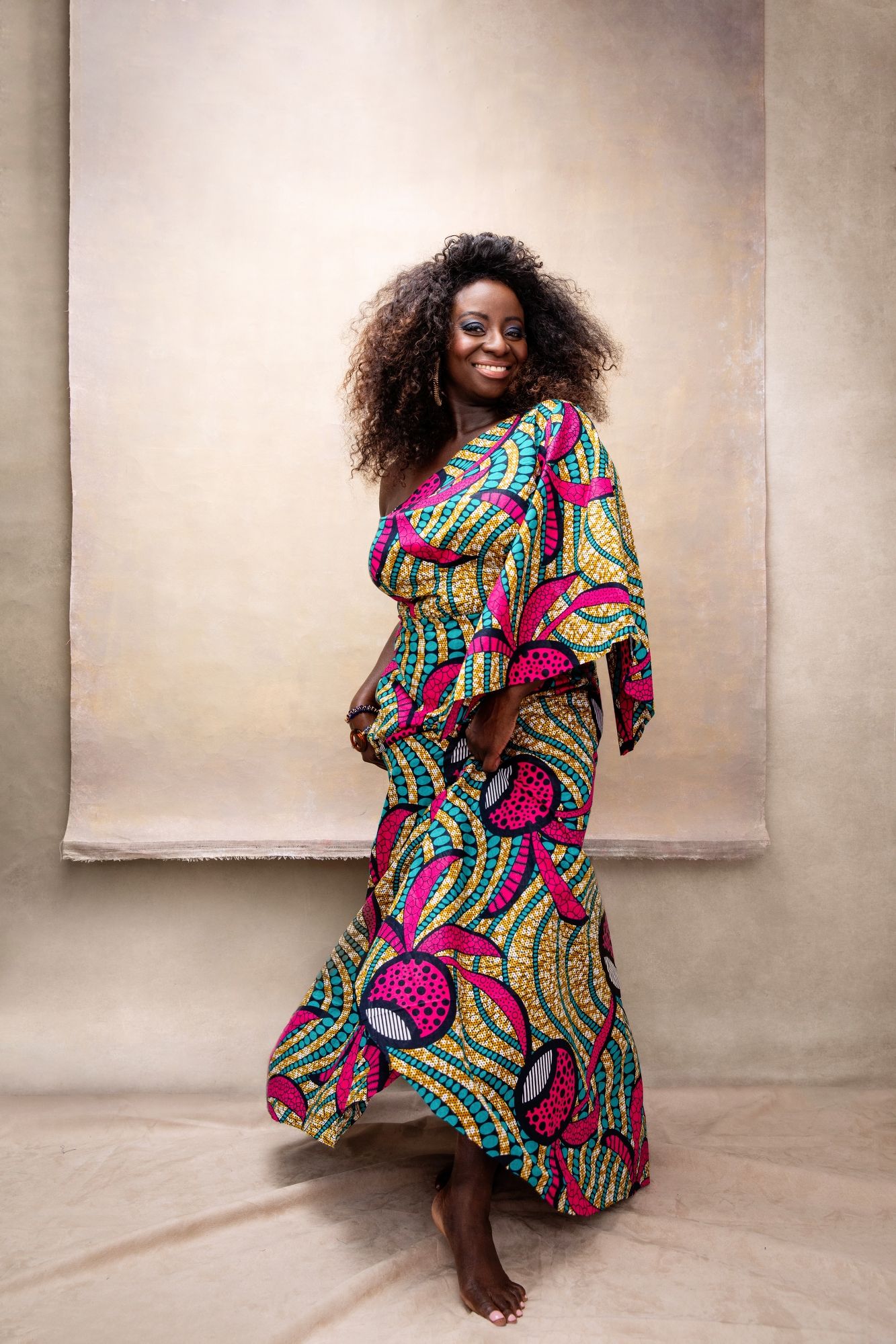 Vibrant African print dress flowing in motion against a neutral studio background.