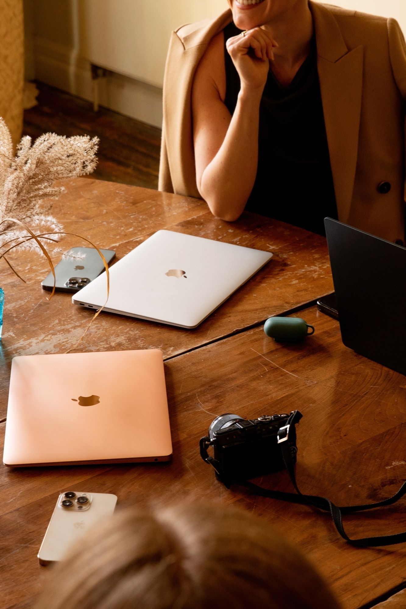 MacBooks and office supplies arranged on a rustic wooden table in warm lighting.
