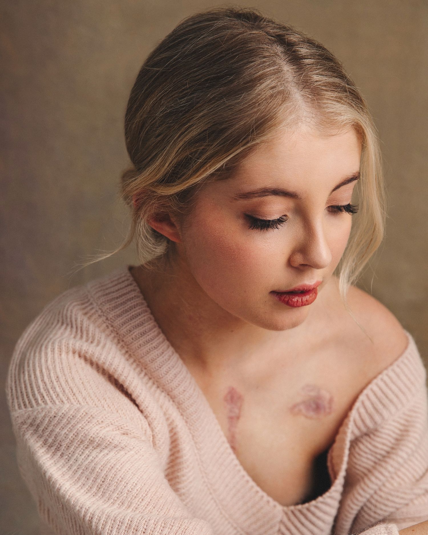 Intimate portrait series featuring soft pink sweater and delicate lighting.