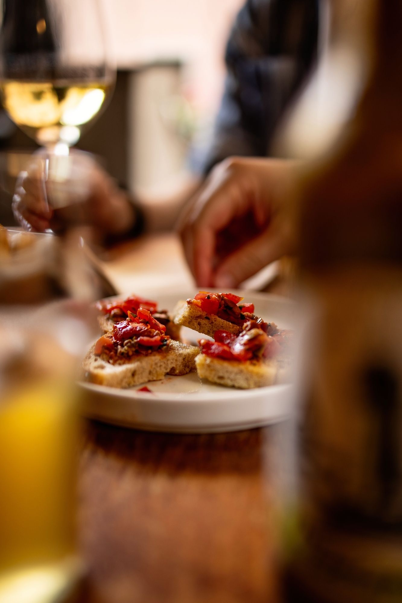 Close-up of bruschetta topped with red toppings and garnishes on a white plate.