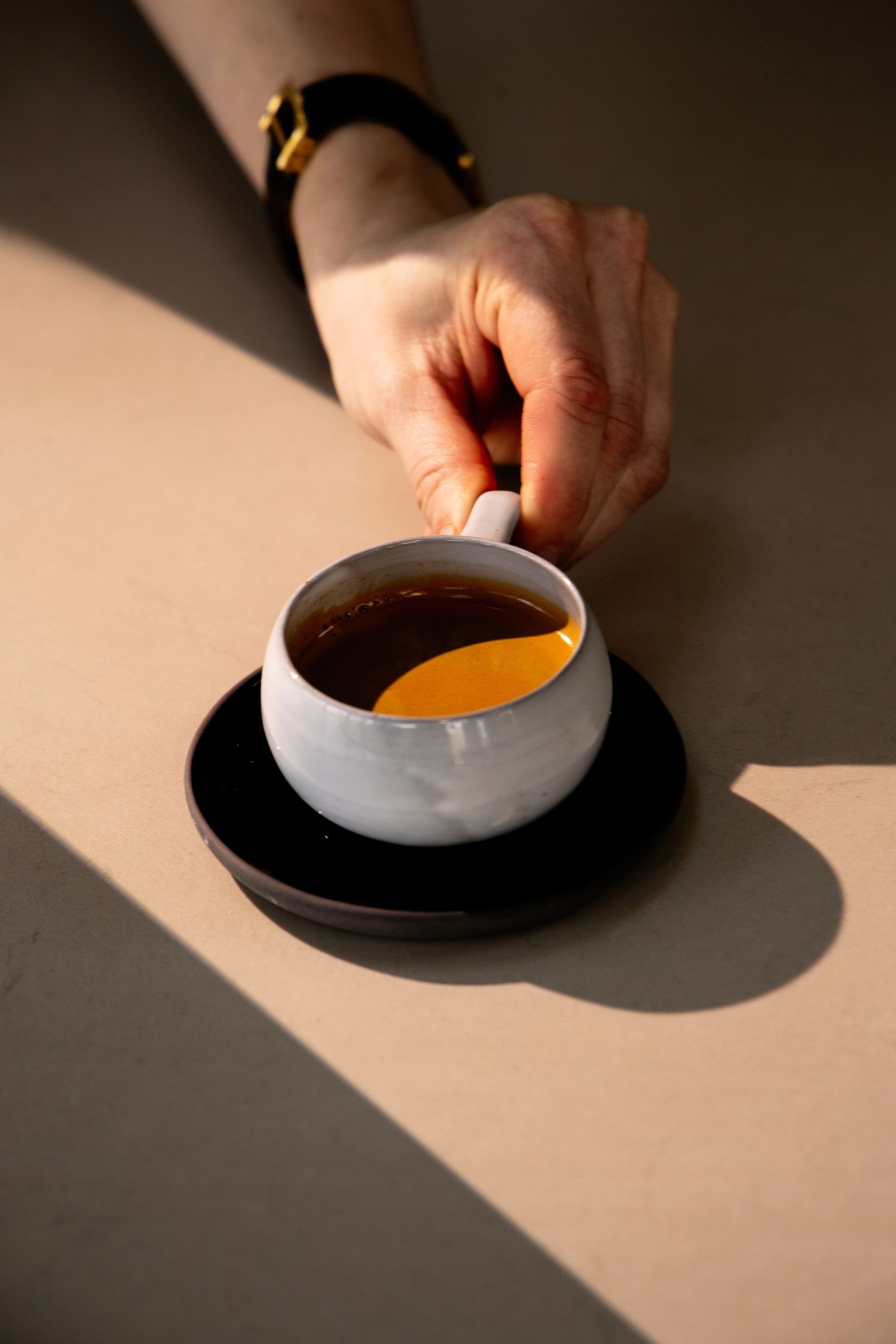 A series of minimalist photos showing a white bowl with orange liquid casting dramatic shadows on a light surface.