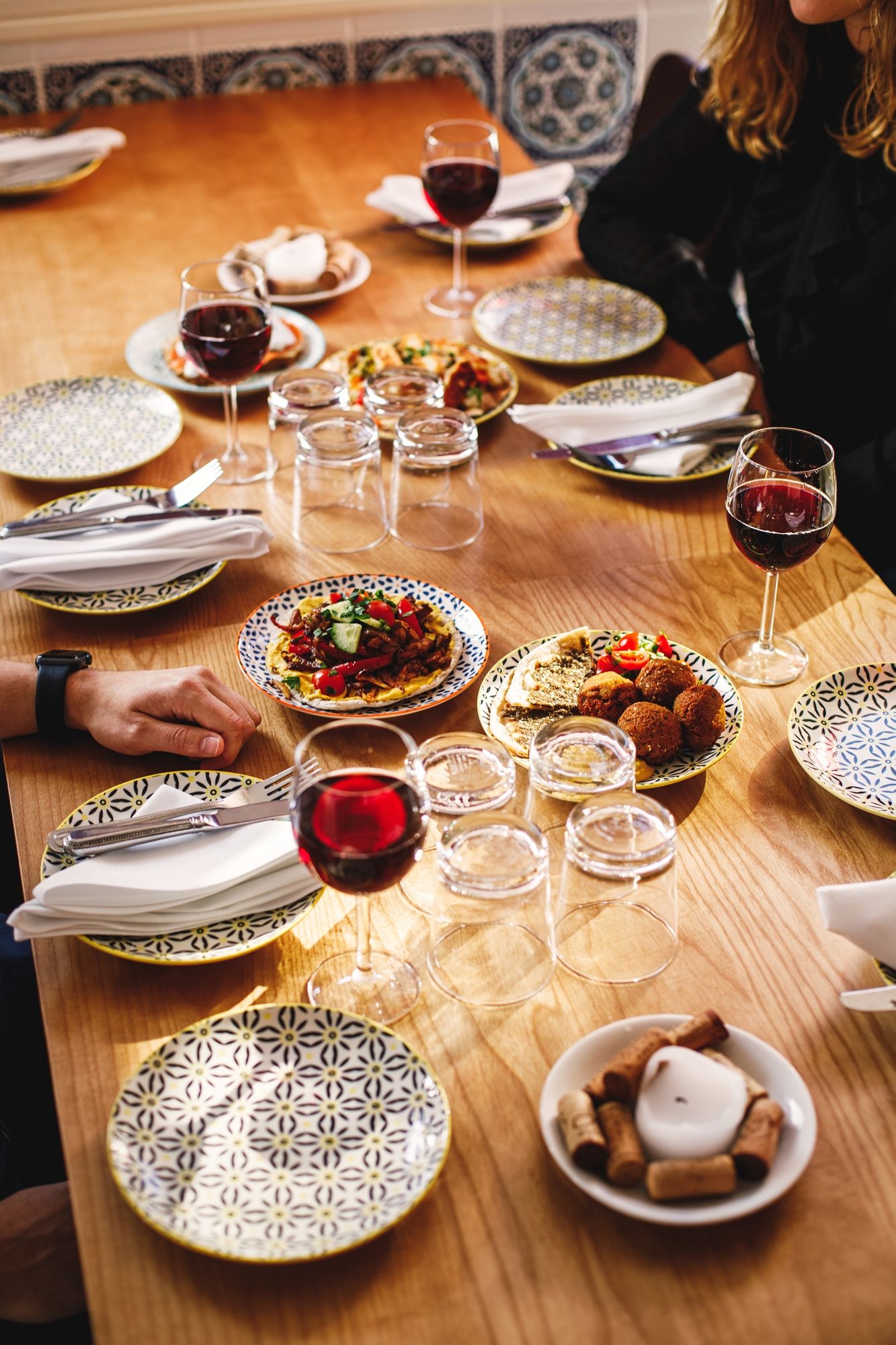 Elegant dinner table setting with patterned plates, wine glasses, and appetizers.