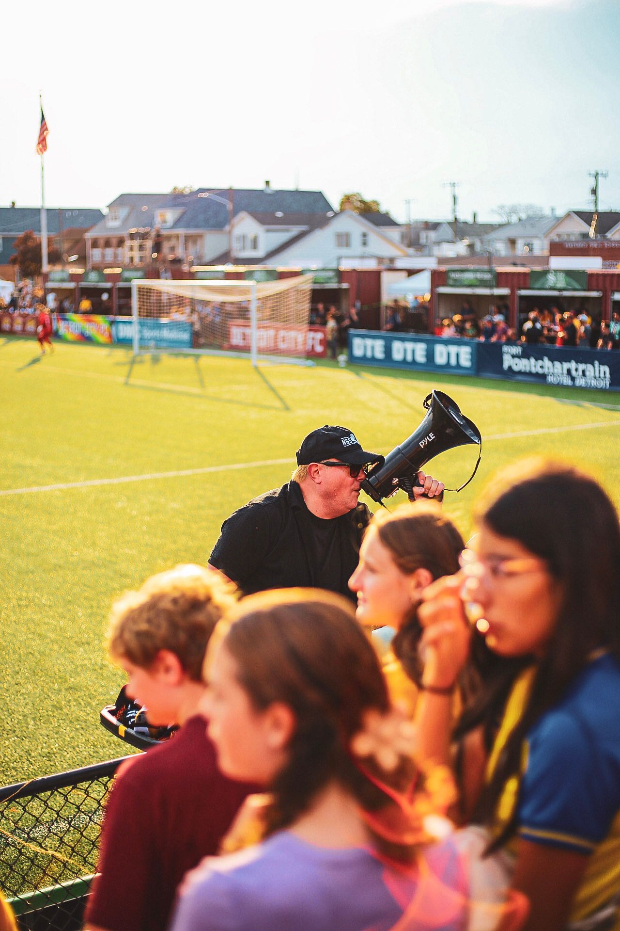 Man with megaphone leading fan chants at a Detroit City FC soccer game at Keyworth Stadium.