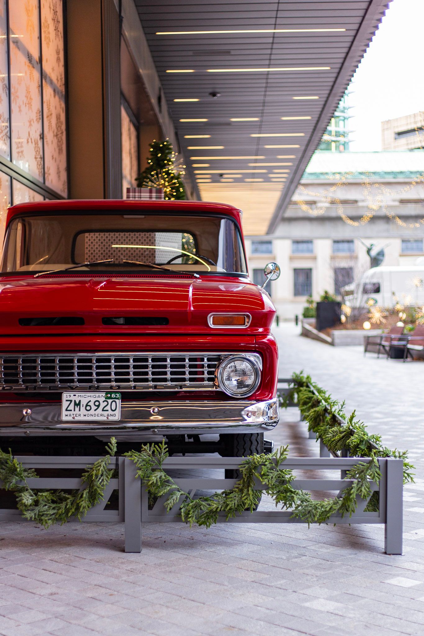 Vintage red Chevrolet pickup truck decorated with garland displayed outdoors in a festive holiday setting.