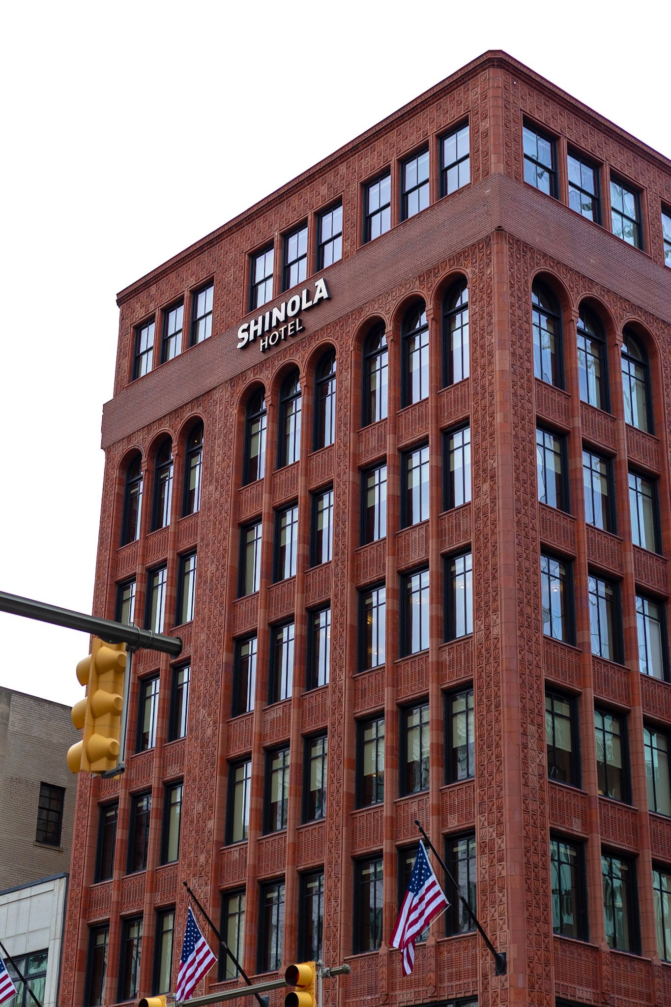 Shinola Hotel exterior featuring red brick architecture with arched windows and American flags in Detroit, Michigan.