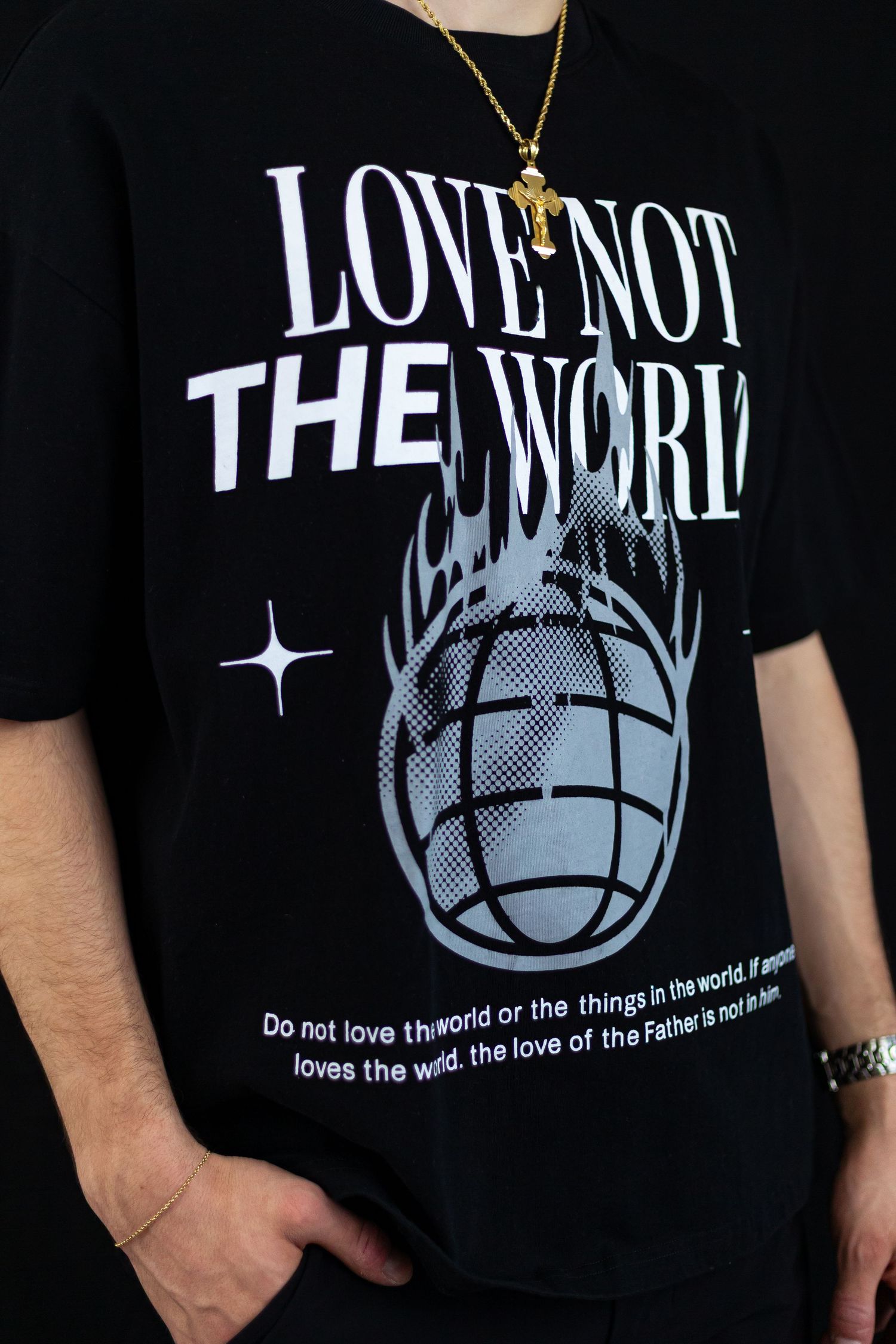 Close-up of black Love Not The World t-shirt with flaming globe graphic and biblical scripture text.