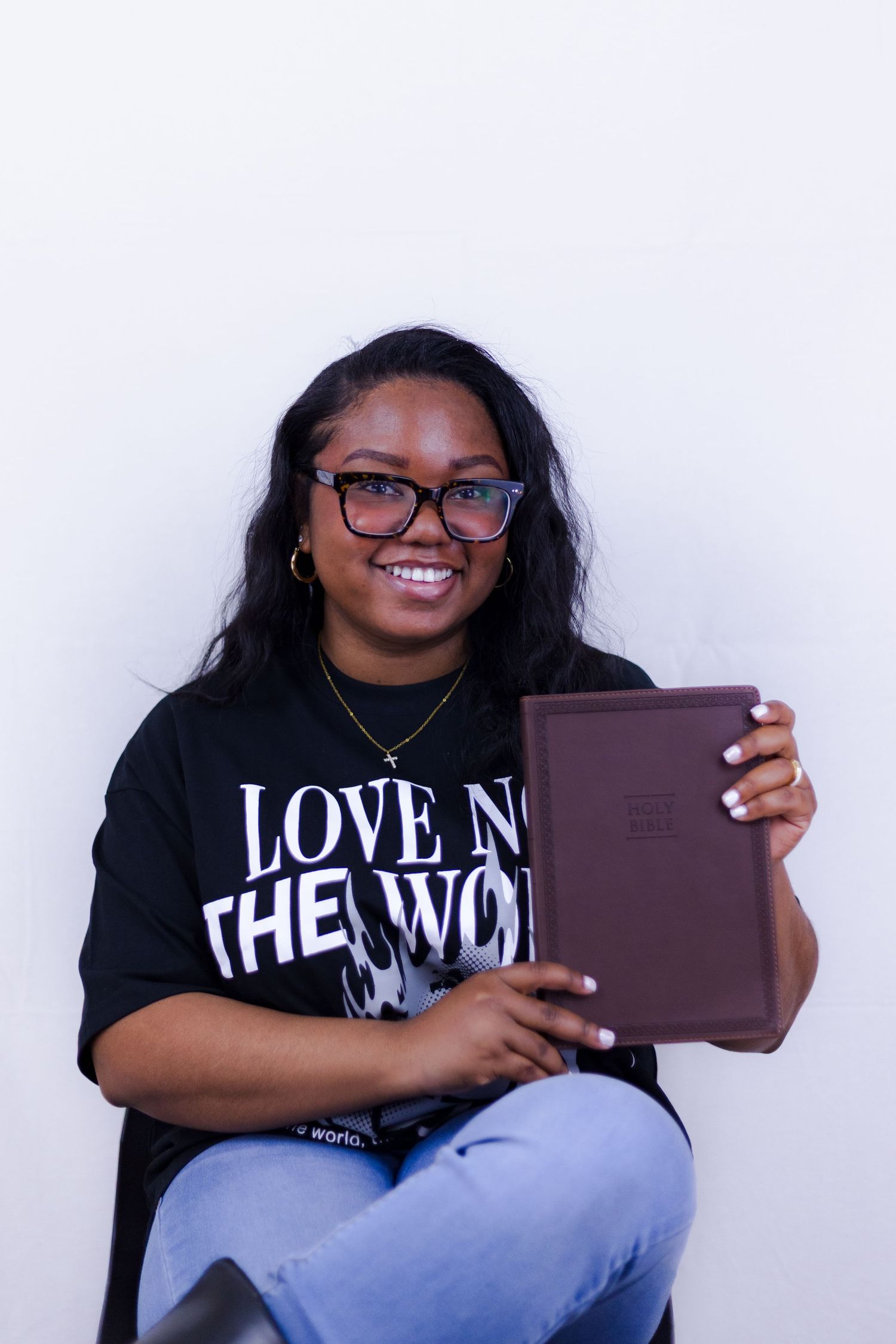 Smiling woman holding a Bible wearing a black Love Not The World graphic tee.