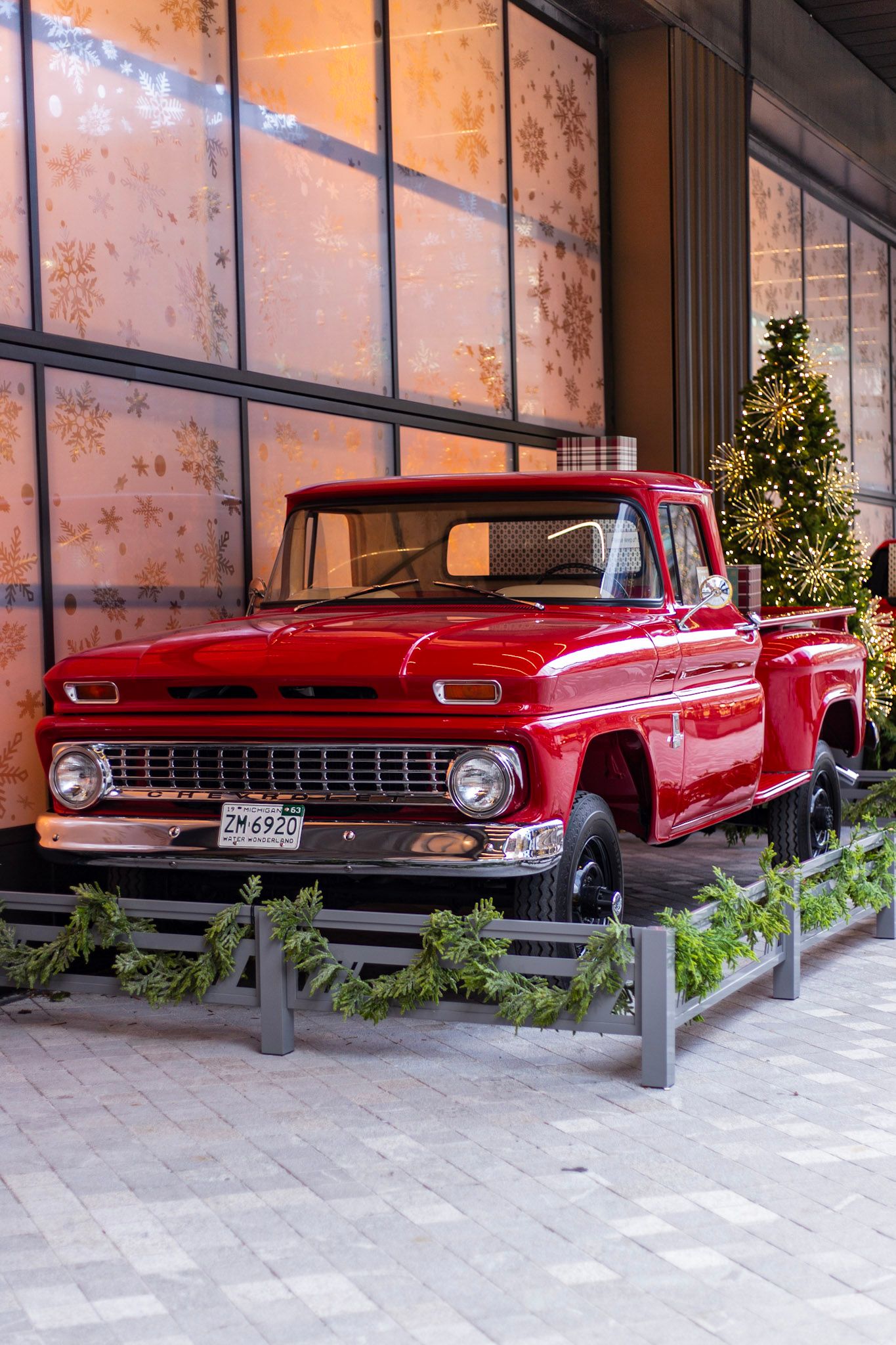 Classic restored red Chevrolet pickup truck with holiday Christmas tree decorations outside Shinola Hotel Detroit.
