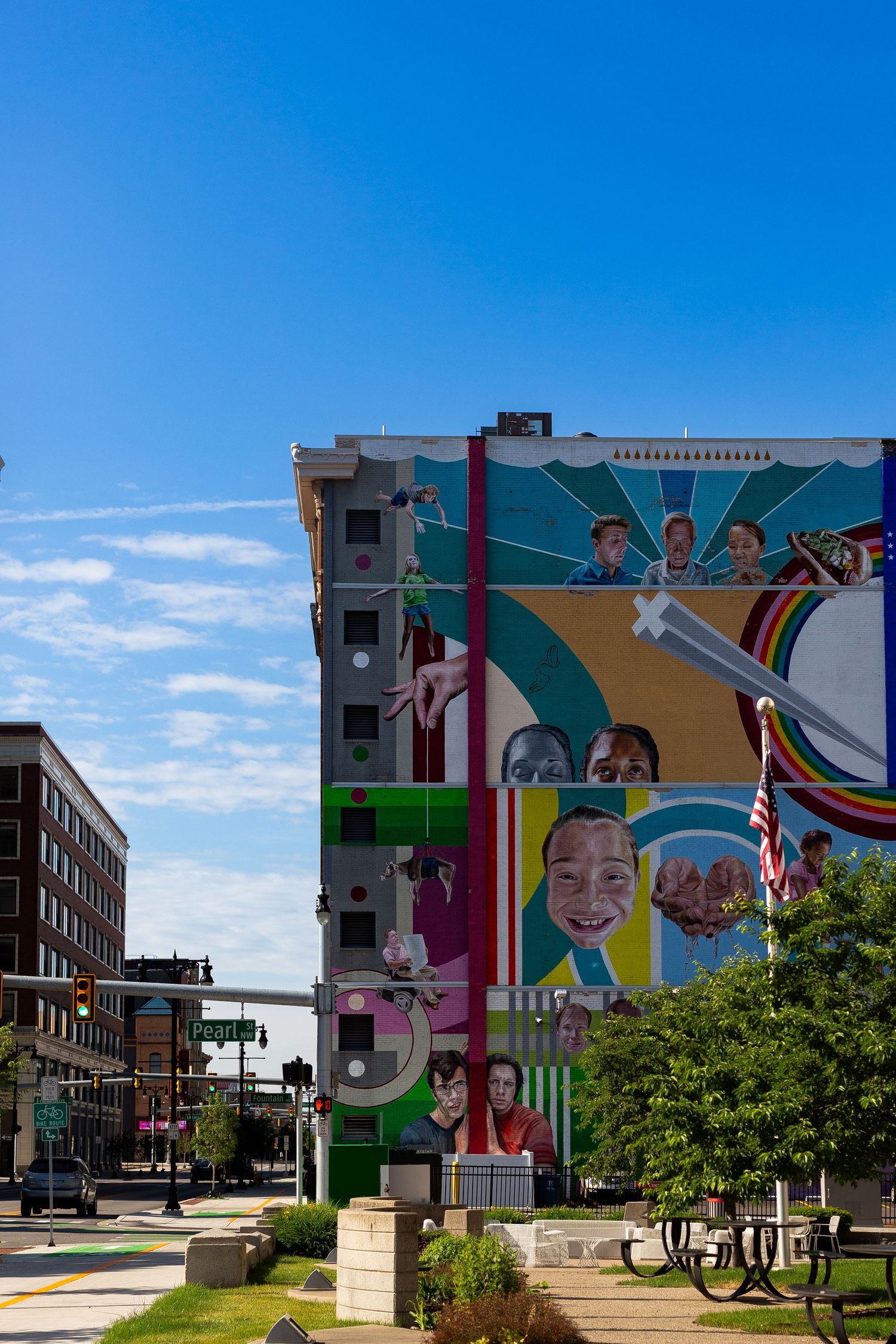 Colorful large-scale mural on urban building facade depicting diverse people in vibrant downtown cityscape.
