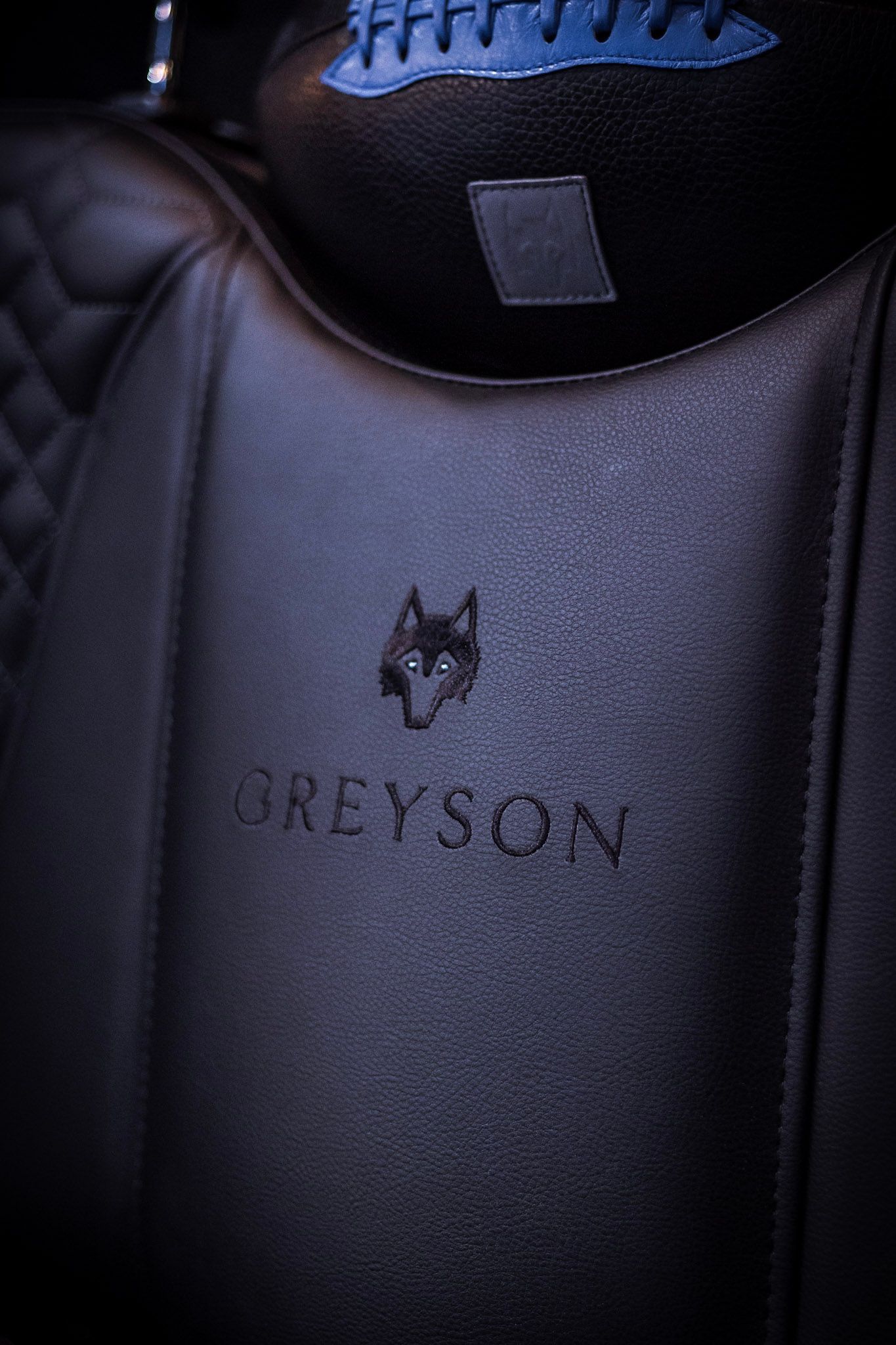 Black leather golf bag embossed with Greyson brand logo featuring a wolf illustration in dark lighting.