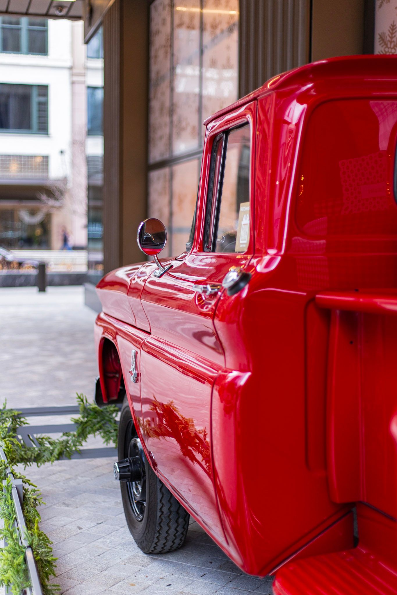 Side view of a brilliantly restored classic red Chevrolet pickup truck with round mirror outside hotel.
