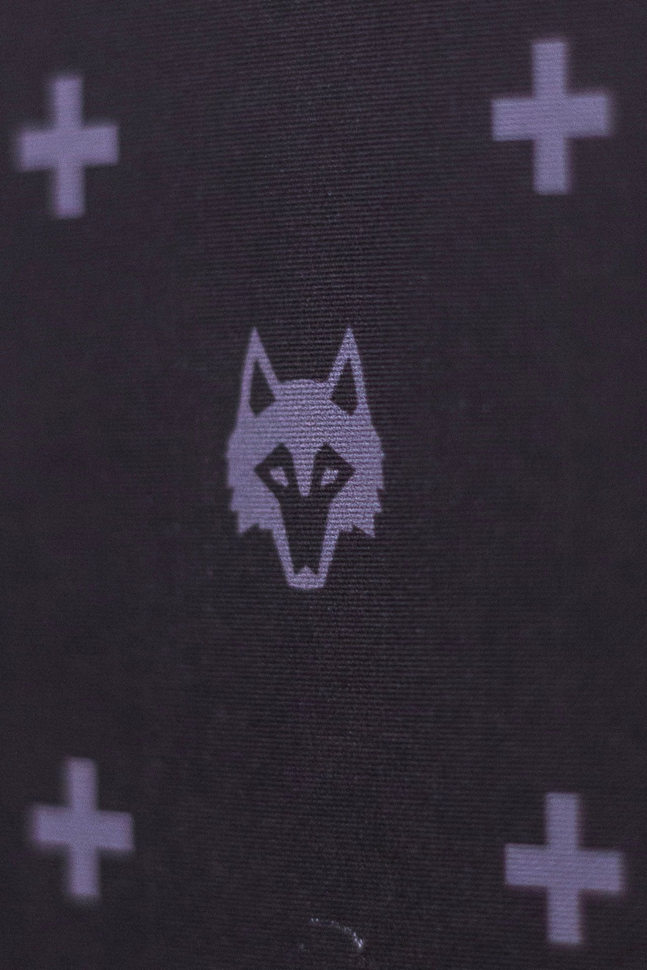Dark fabric pattern featuring wolf head logo surrounded by cross symbols in gray.