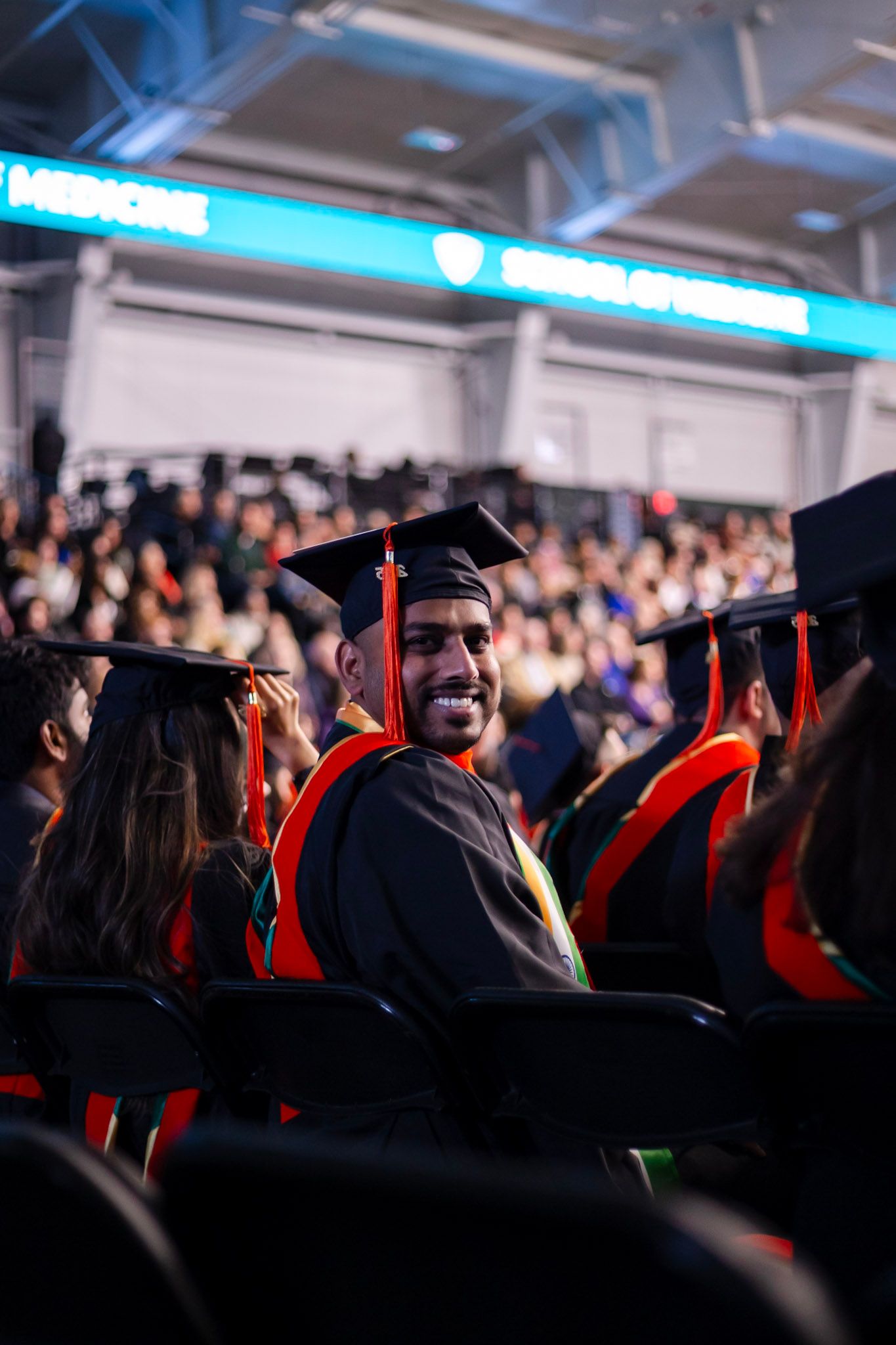 Happy graduate in black cap and gown smiling back at camera during Wayne State University commencement ceremony.