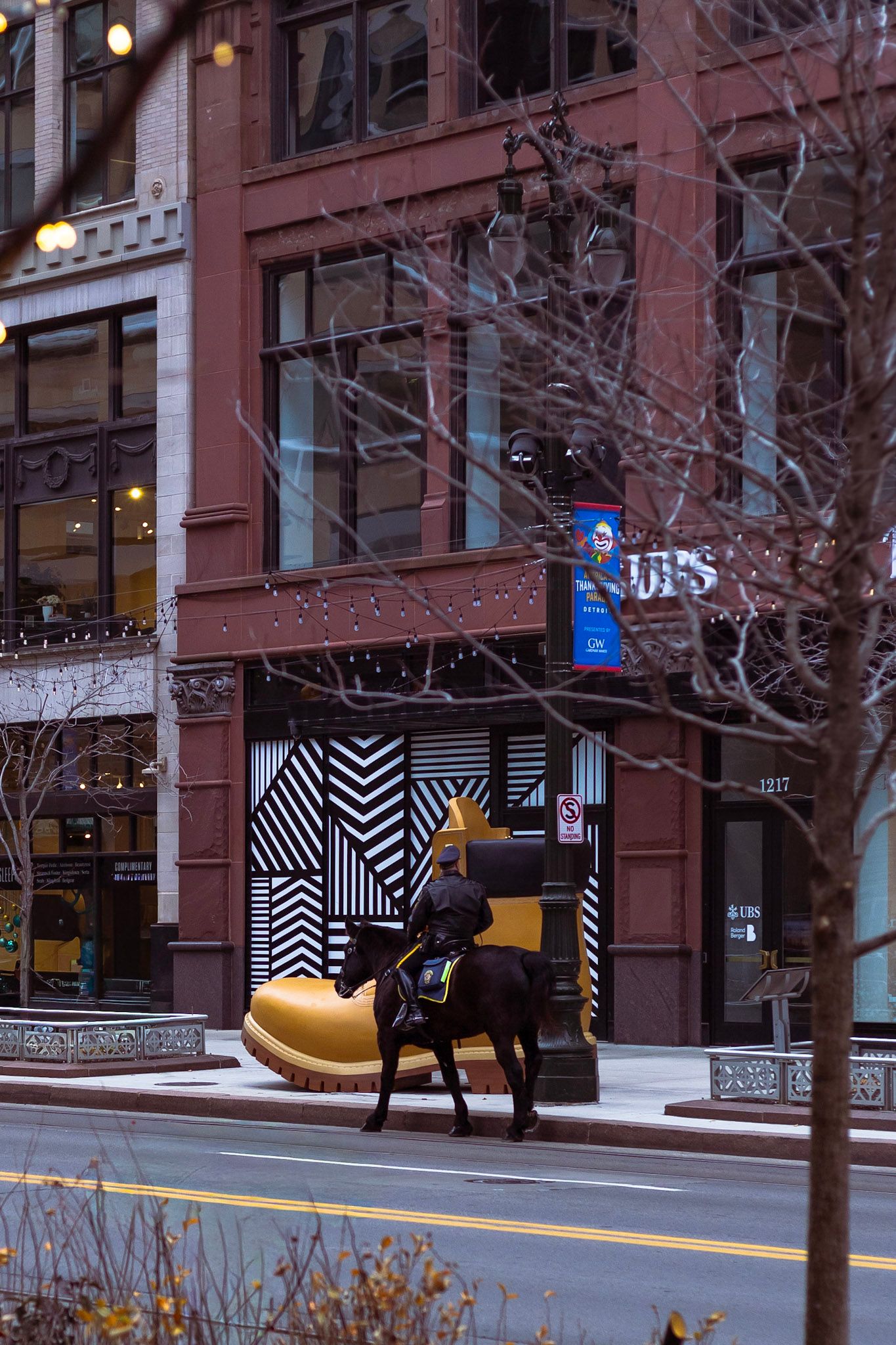 A black horse sculpture sits beside a giant yellow shoe outside a brick building with geometric black and white storefront design.