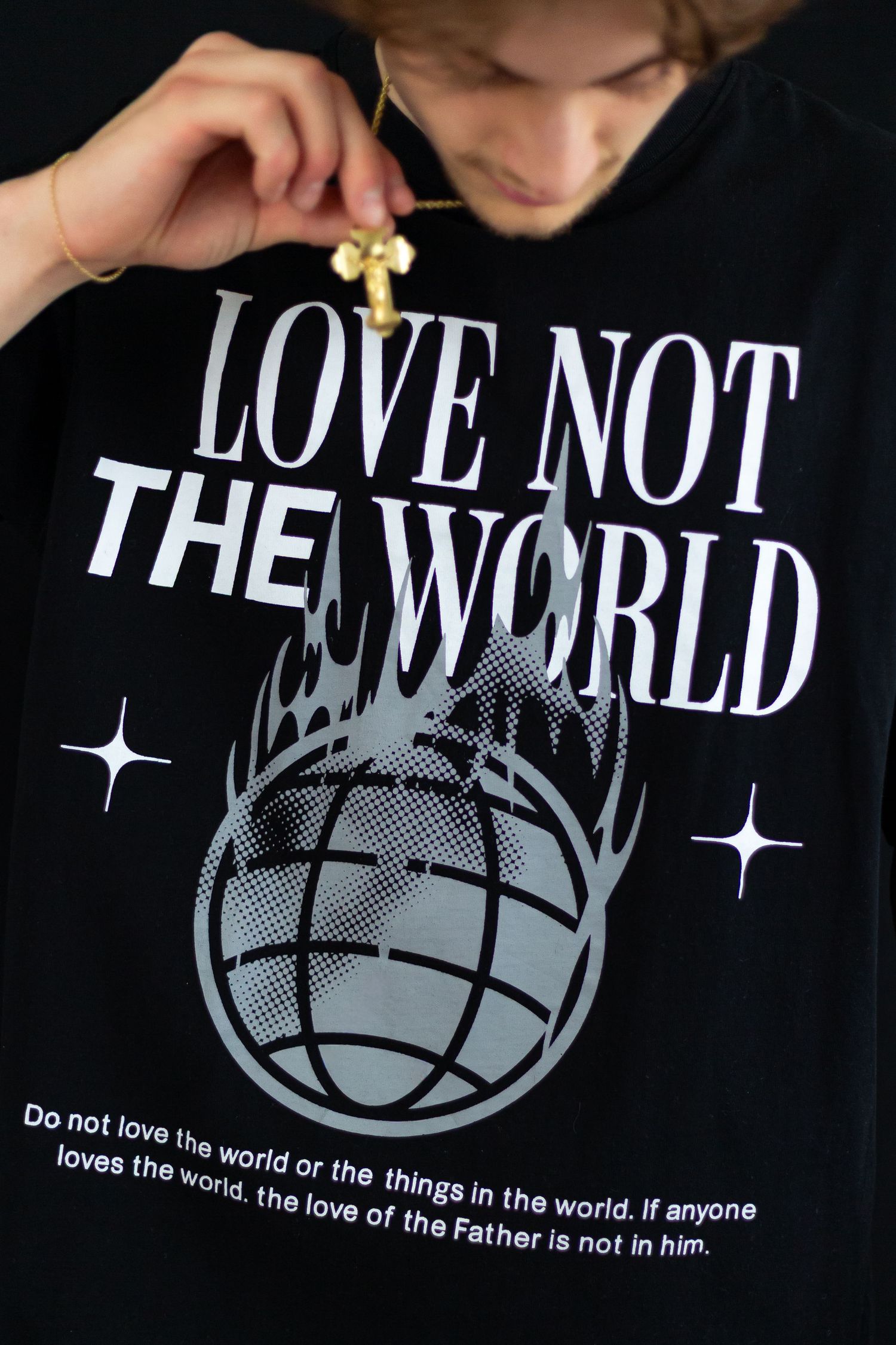 Close-up of black Love Not The World t-shirt with flaming globe graphic and 1 John 2:15 scripture.