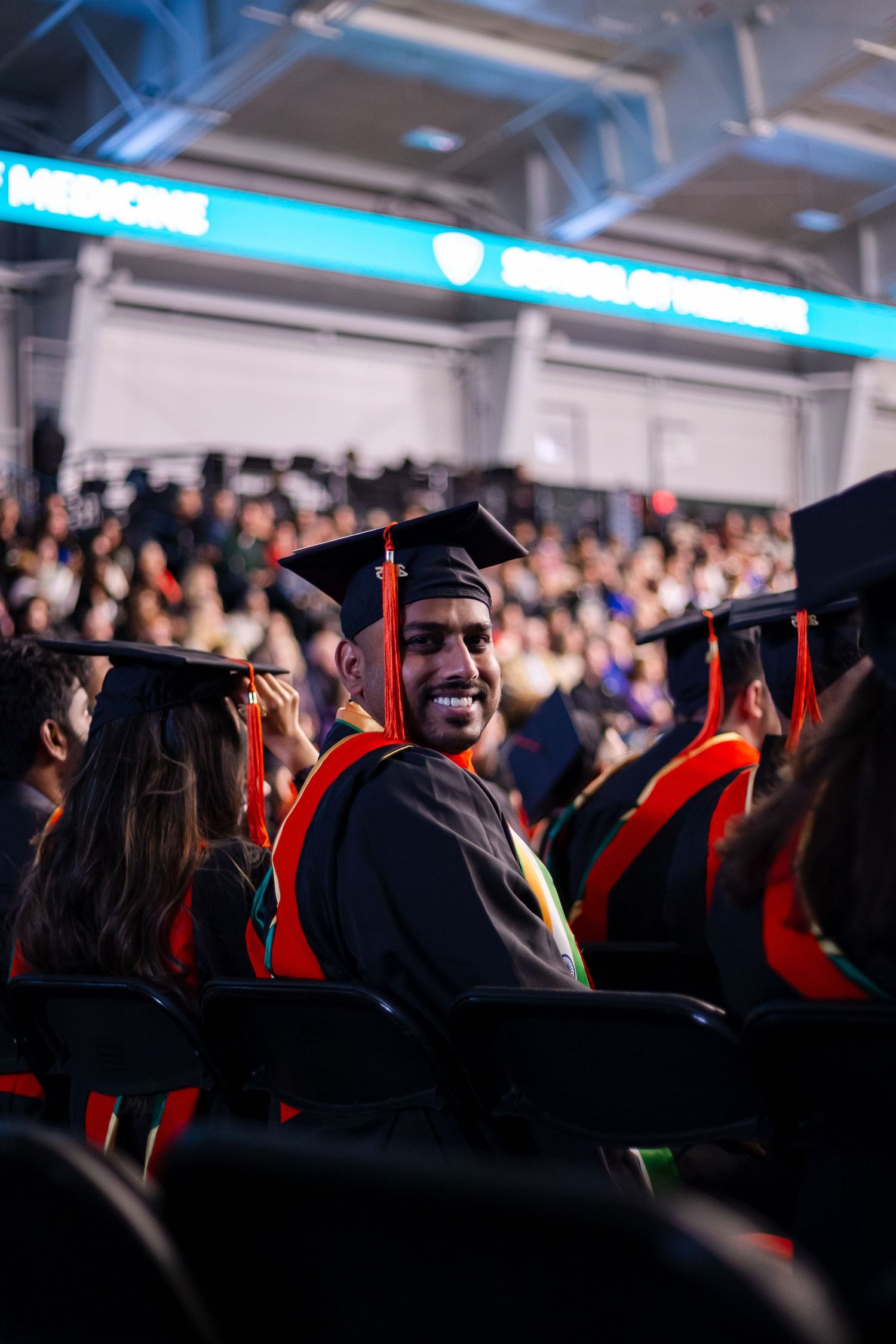 Smiling graduate in cap and gown at Wayne State University commencement ceremony indoors.