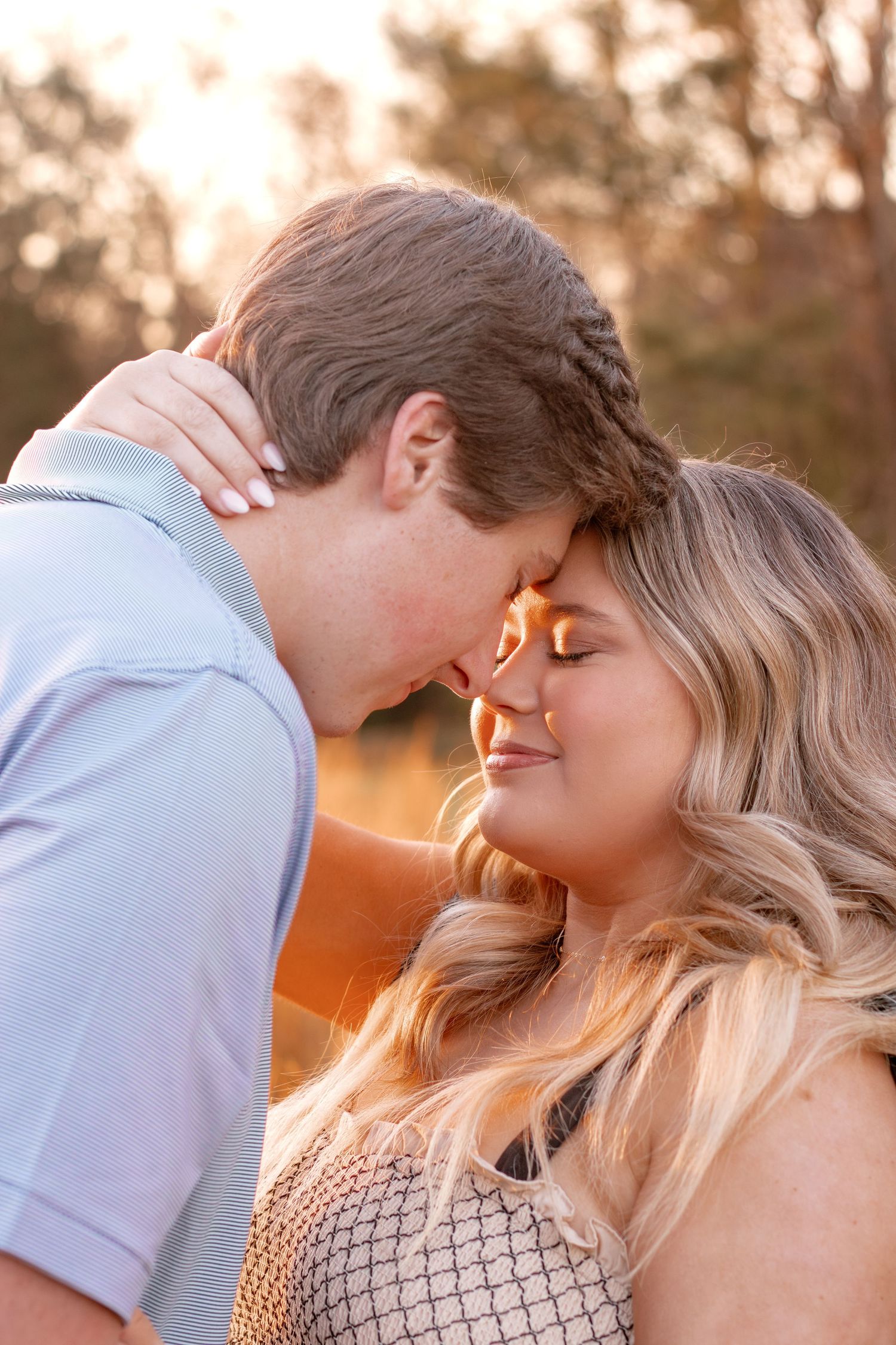 Intimate couple photography during golden hour with soft sunlit glow in the background.