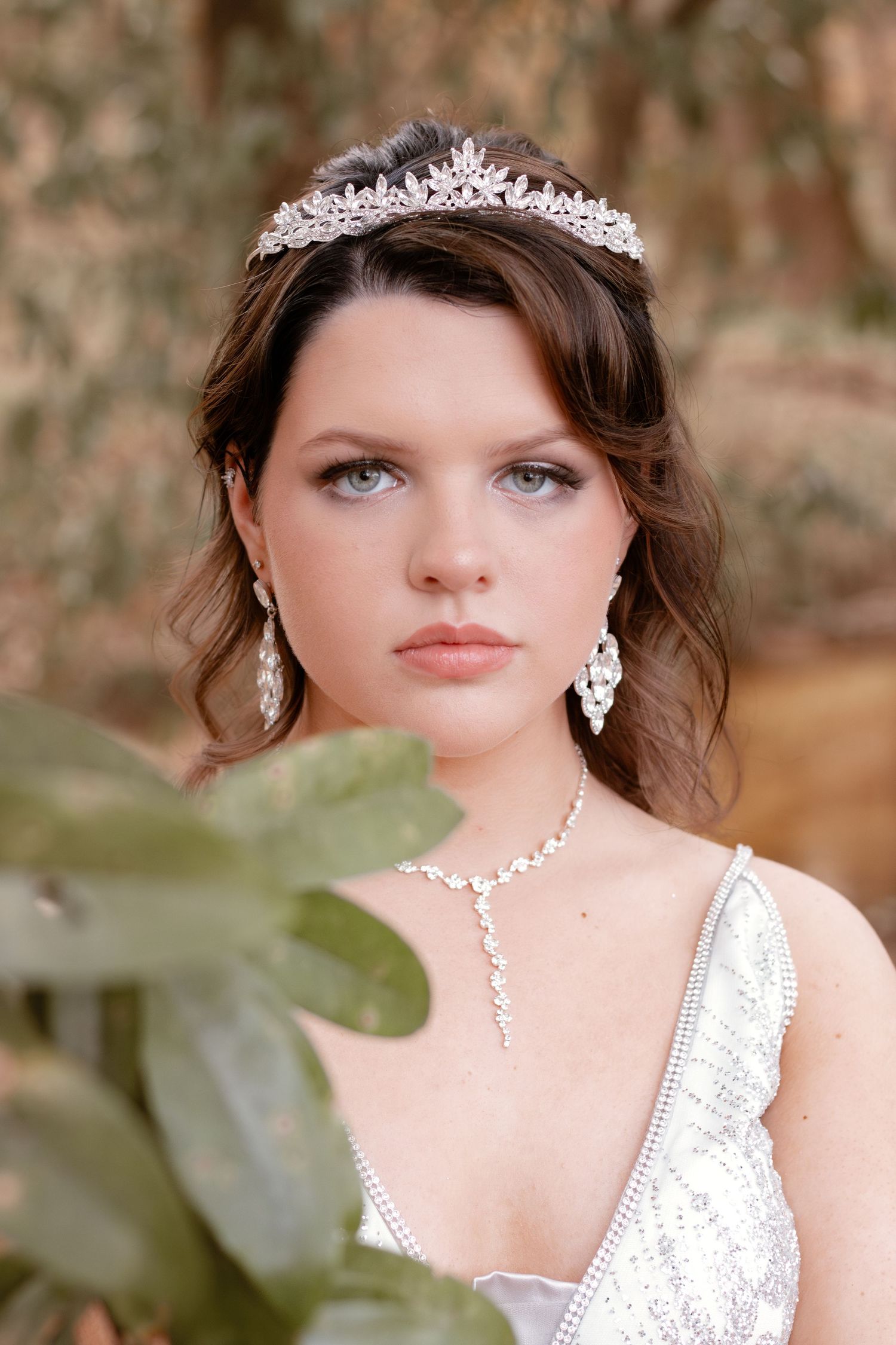 A formal prom portrait with a crystal tiara and white lace gown accessorized with matching jewelry.