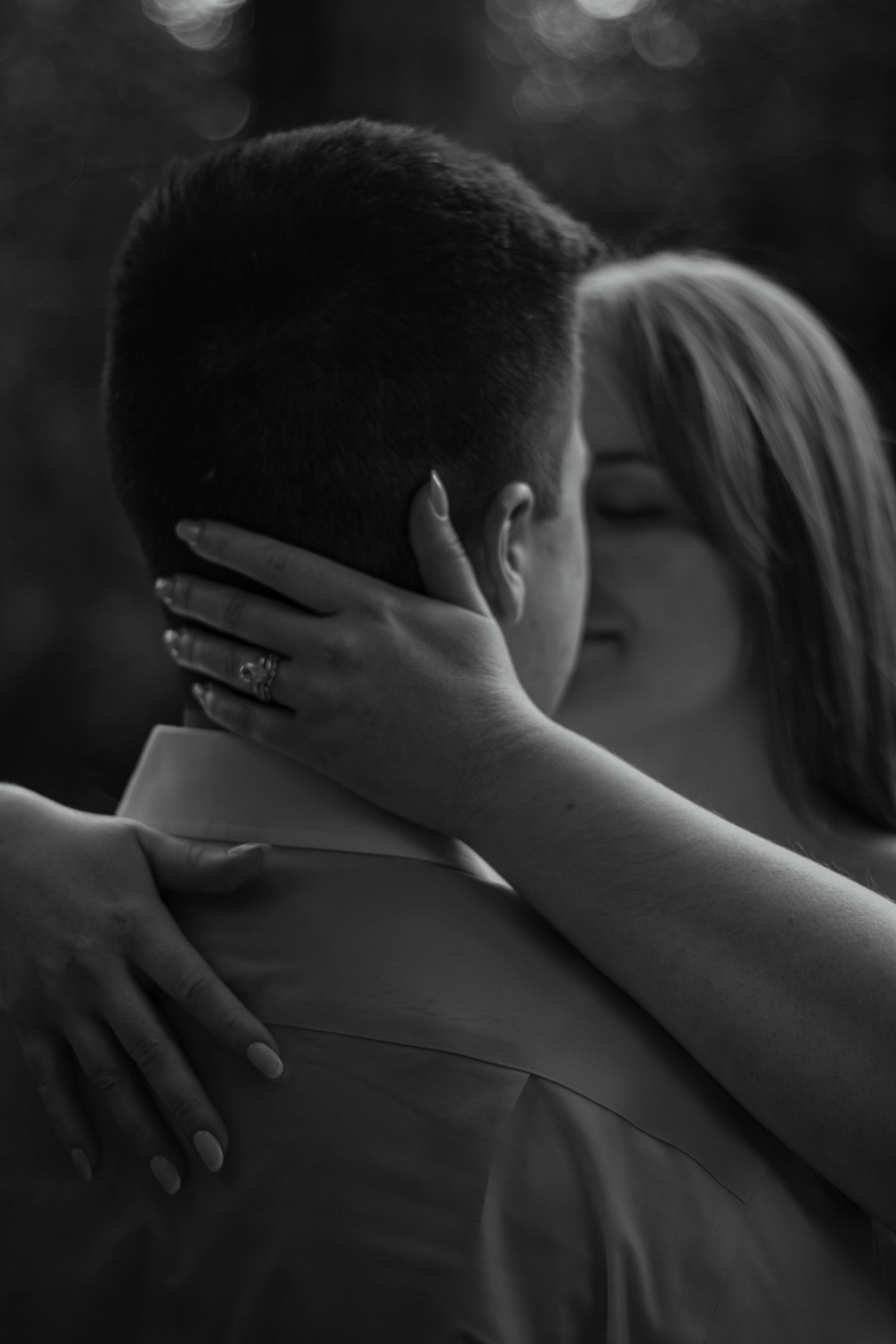 A tender black and white romantic moment as a couple shares an intimate embrace outdoors.
