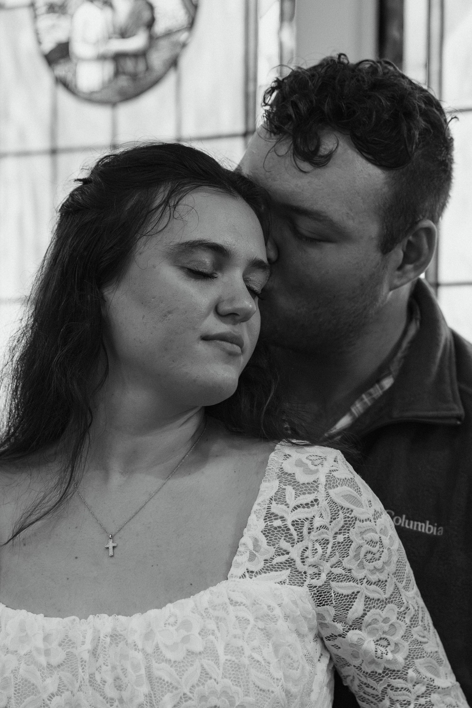Black and white romantic portrait of a couple in an intimate moment, with woman wearing lace dress.